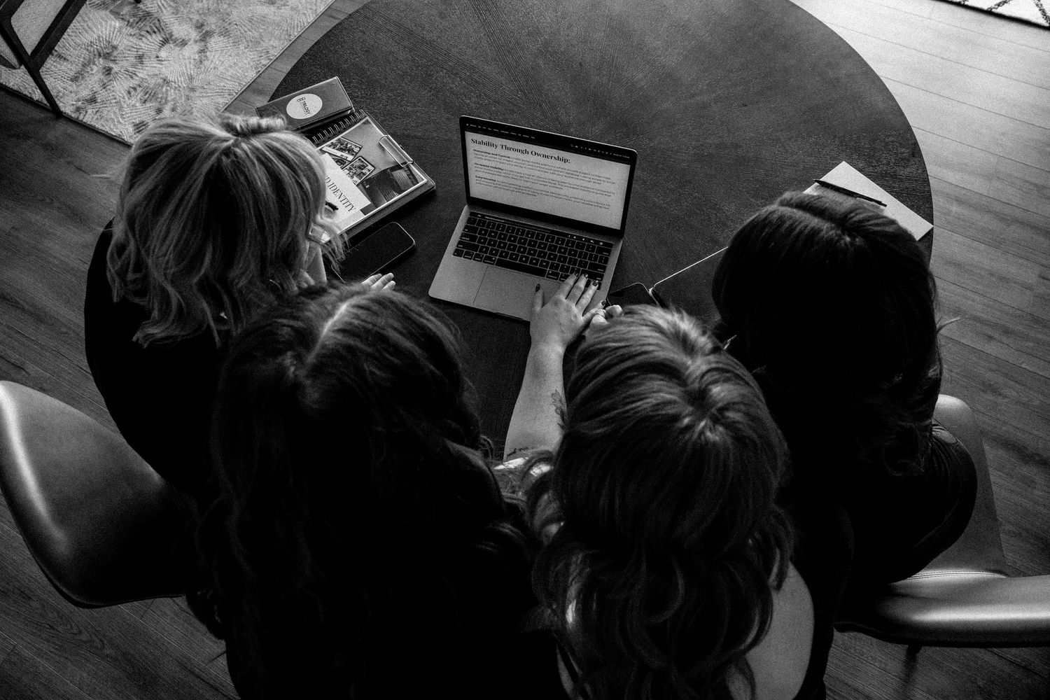 Overhead view of people gathered around a laptop computer in a dark room.