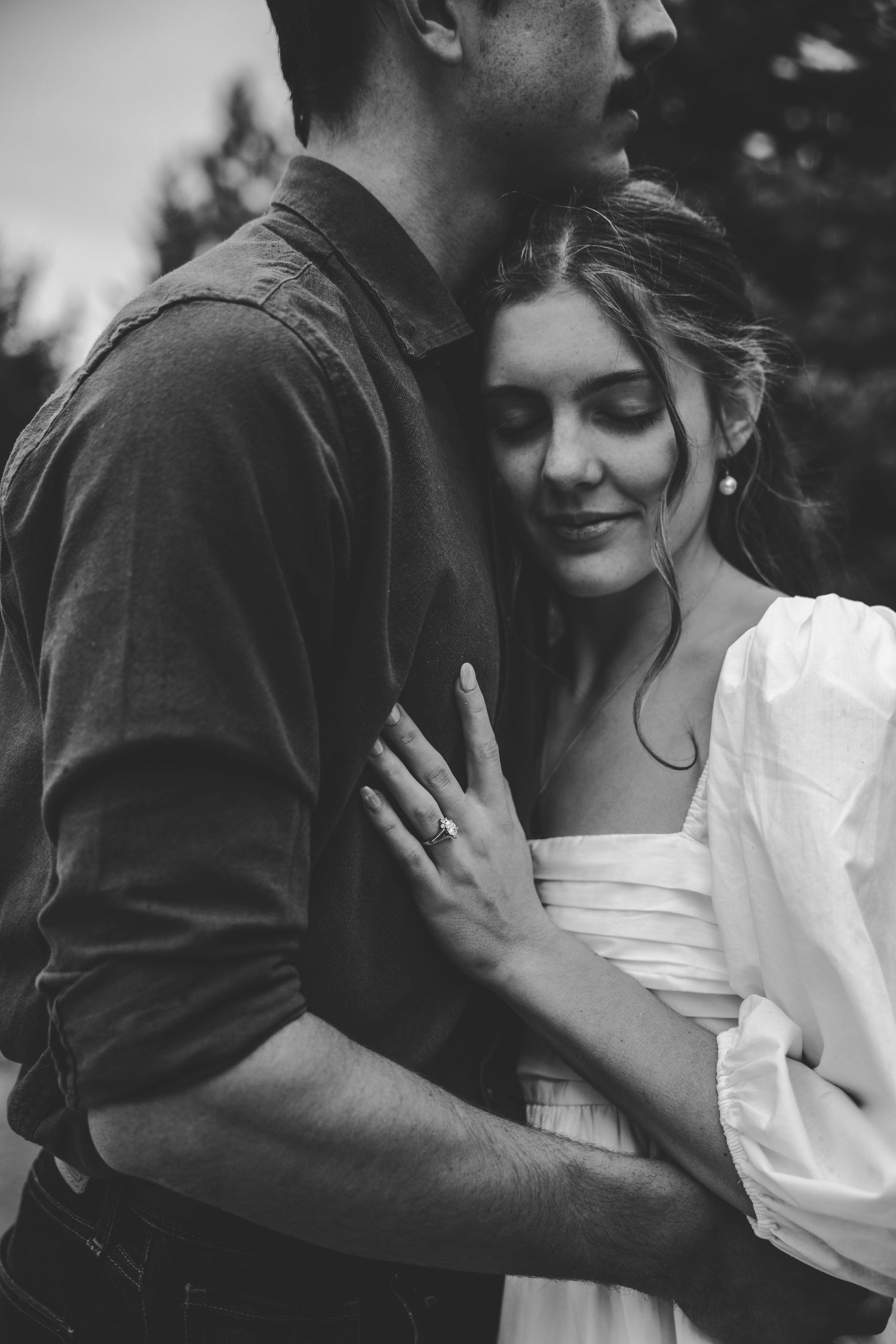 Intimate black and white moment between two people embracing outdoors.