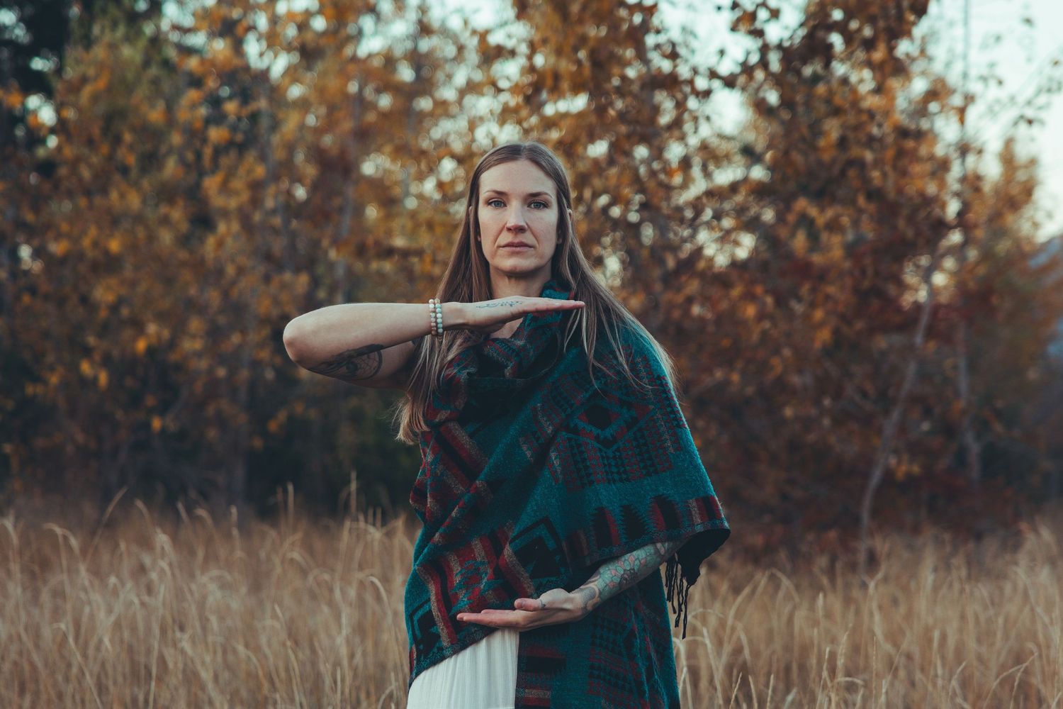 Person in green dress posing gracefully in autumn field with golden light.