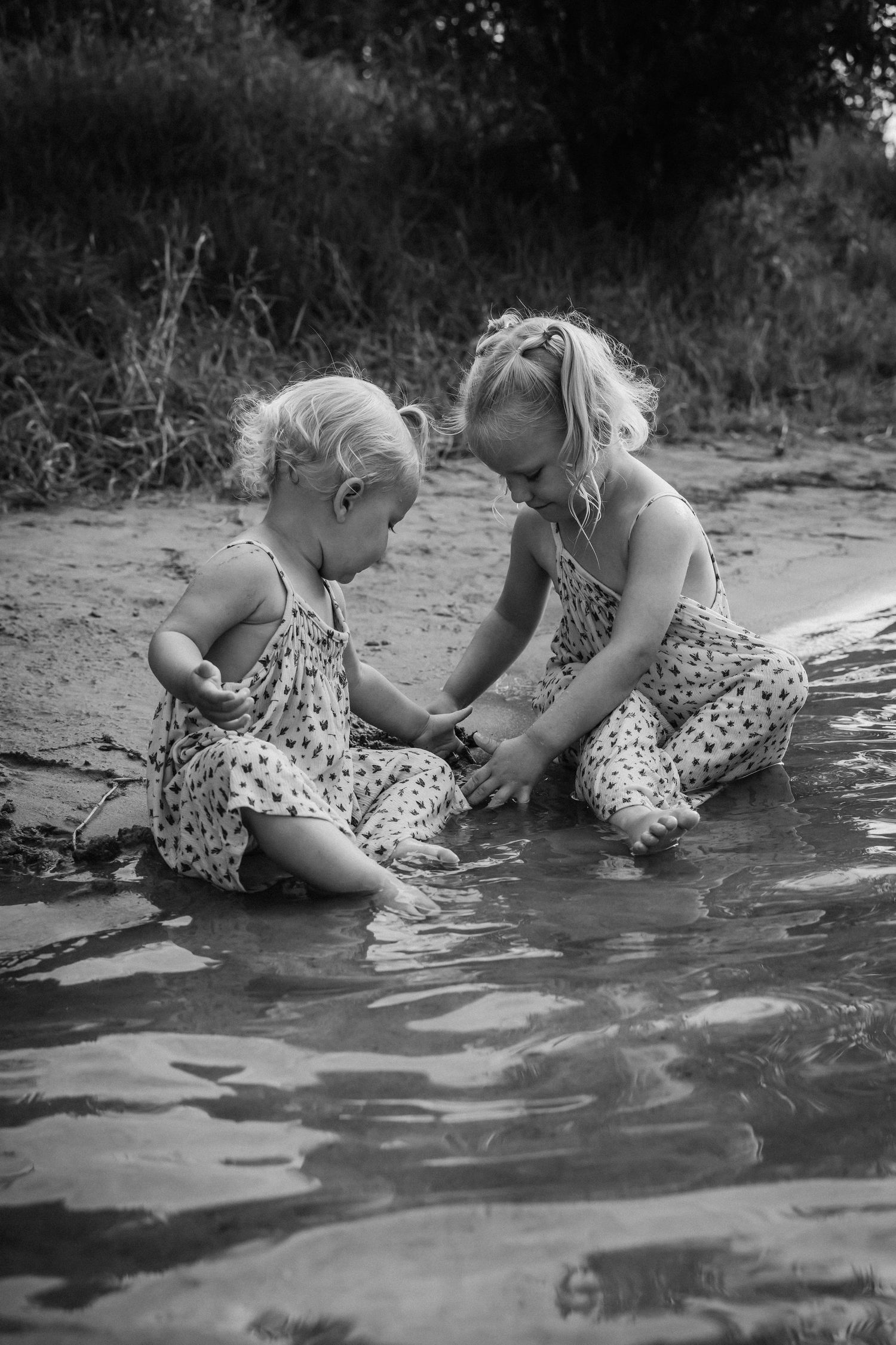 Black and white images of children playing in shallow water at the lake shore.