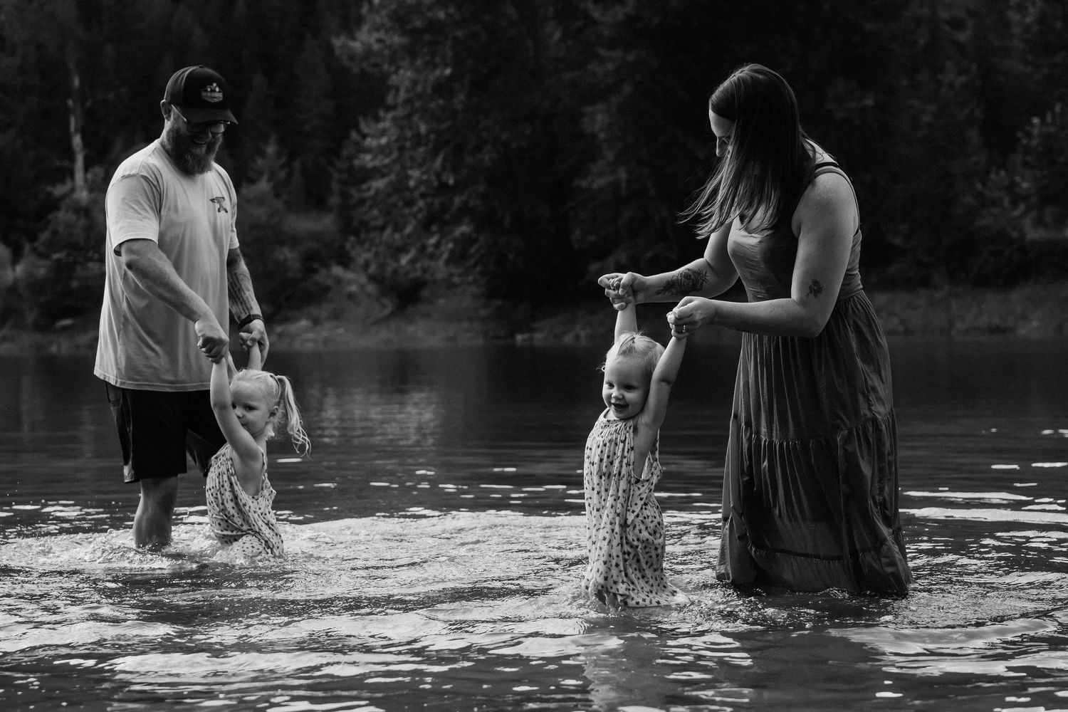 Silhouettes of family members wading and playing in lake water at sunset.