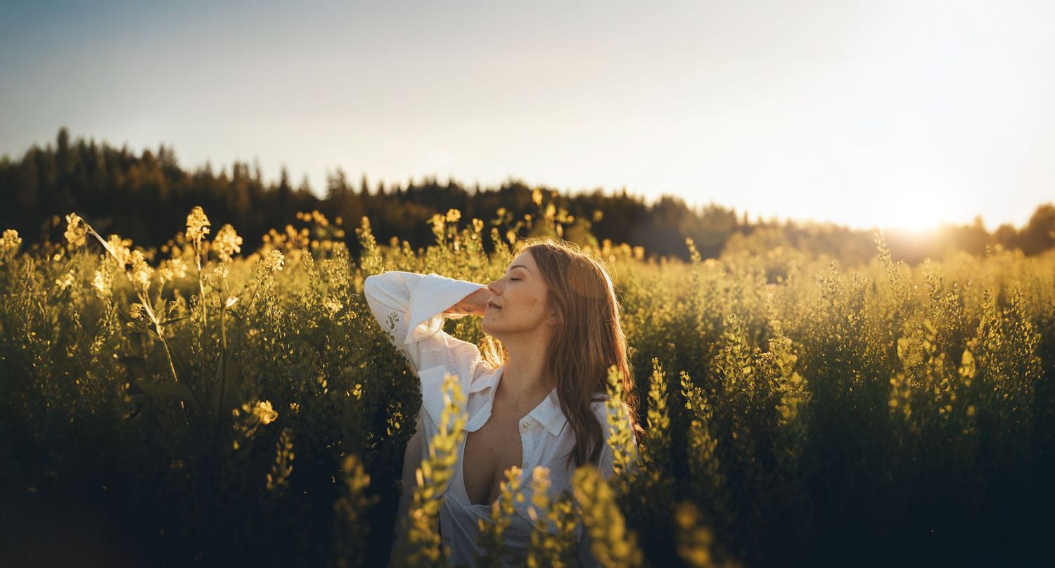 Golden hour portrait session in field of yellow wildflowers at sunset.