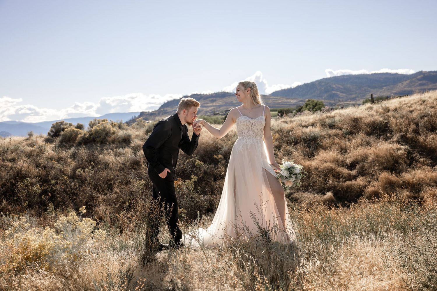 Couple walking through a desert landscape with mountains in the background.