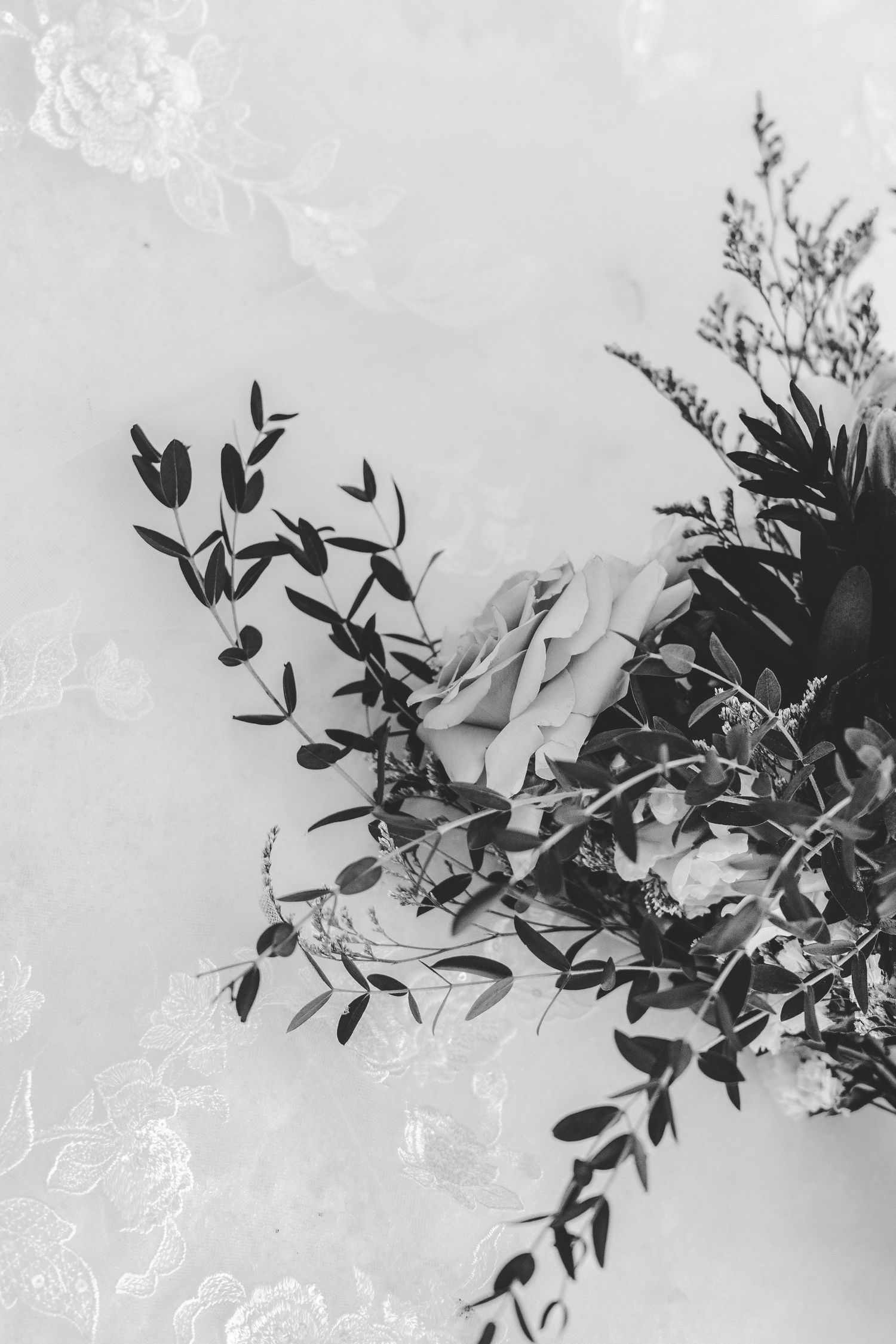 Delicate floral arrangement with greenery and leaves photographed in black and white against snow.