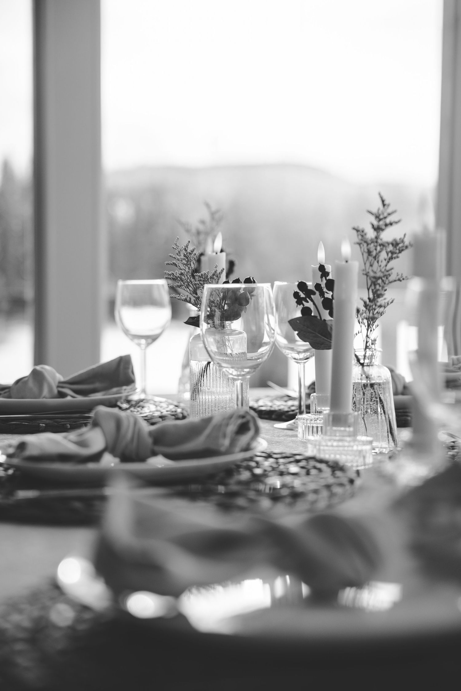 Formal table setting with glassware and floral centerpieces in soft focus black and white.