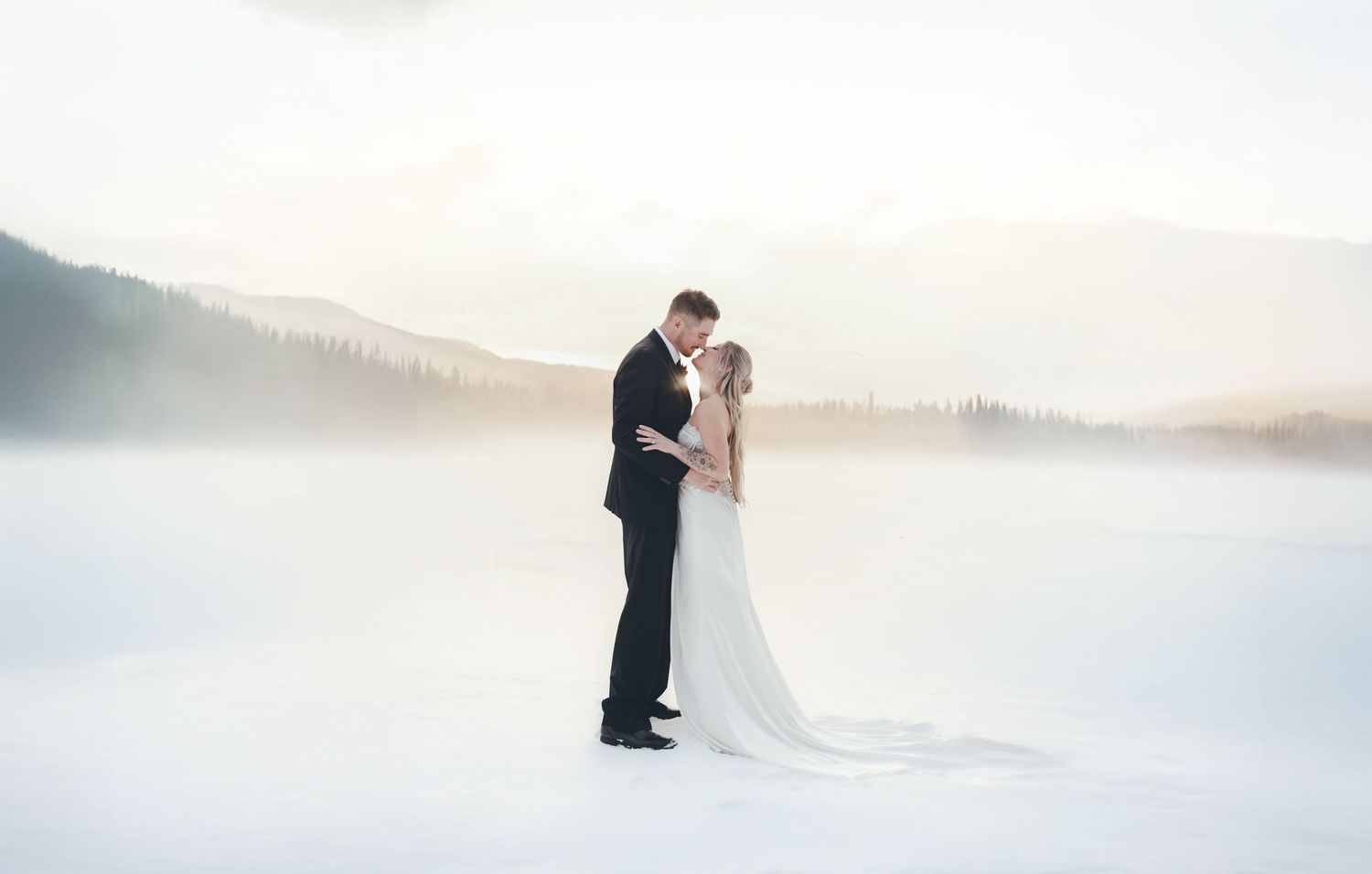 A romantic winter wedding photoshoot in a snowy landscape with soft lighting and dreamy atmosphere.