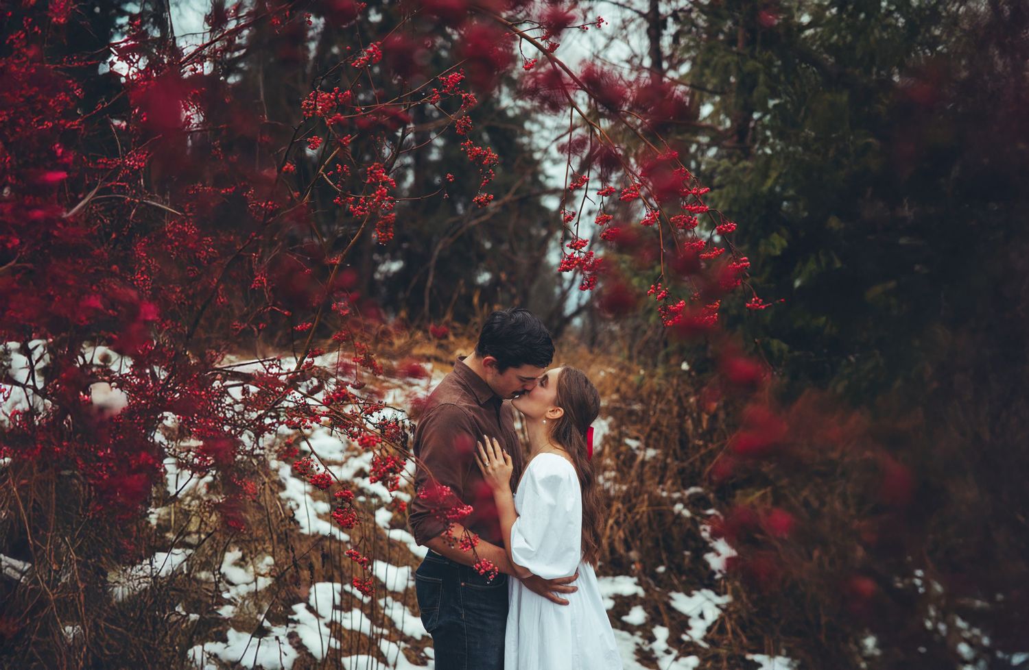 Red autumn foliage frames a romantic moment in a natural outdoor setting.
