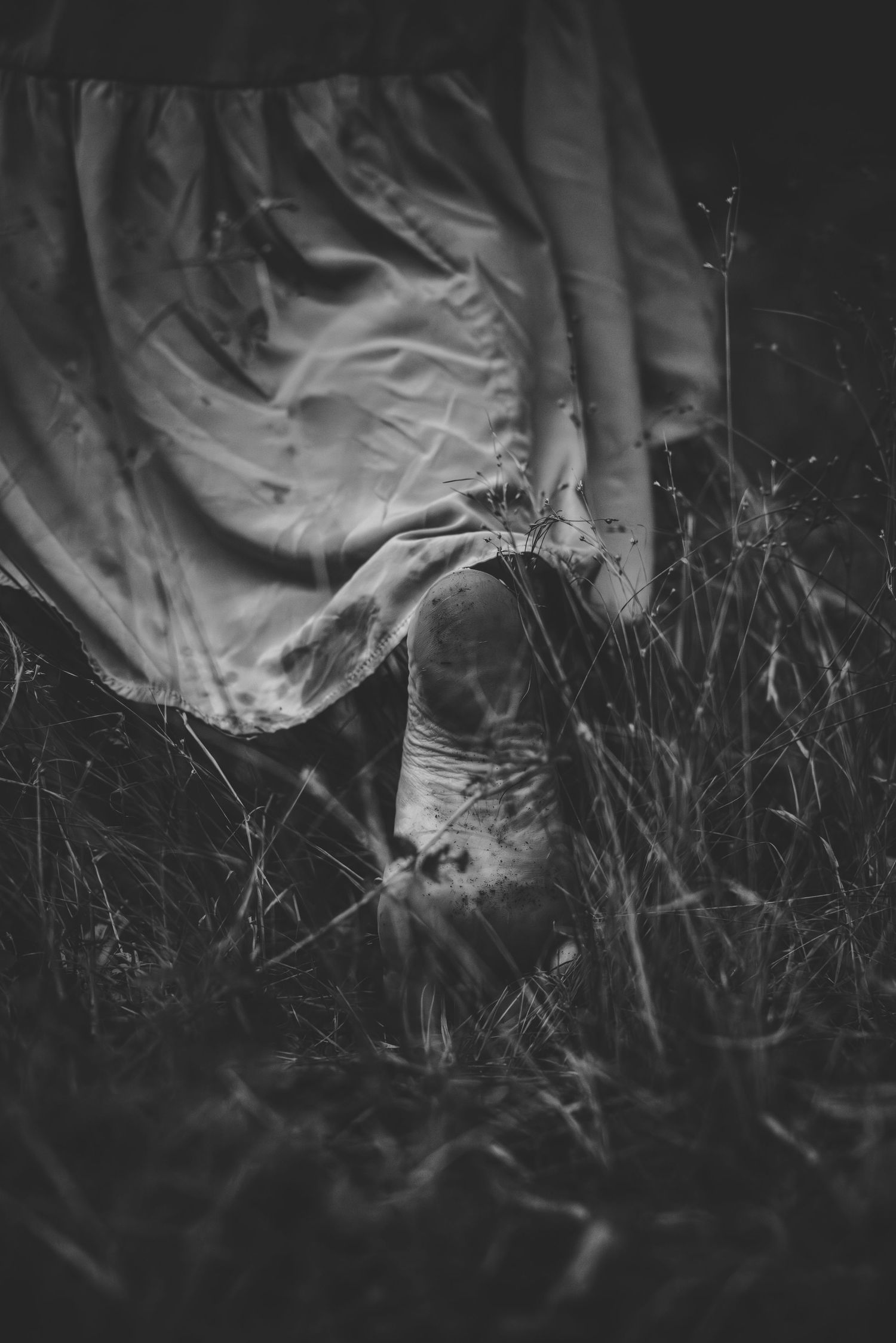 A black and white close-up of fabric against wild grass and flowers.