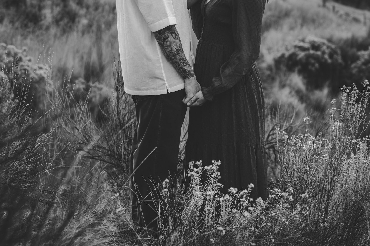 Close-up details of clothing and hands against a natural outdoor backdrop.