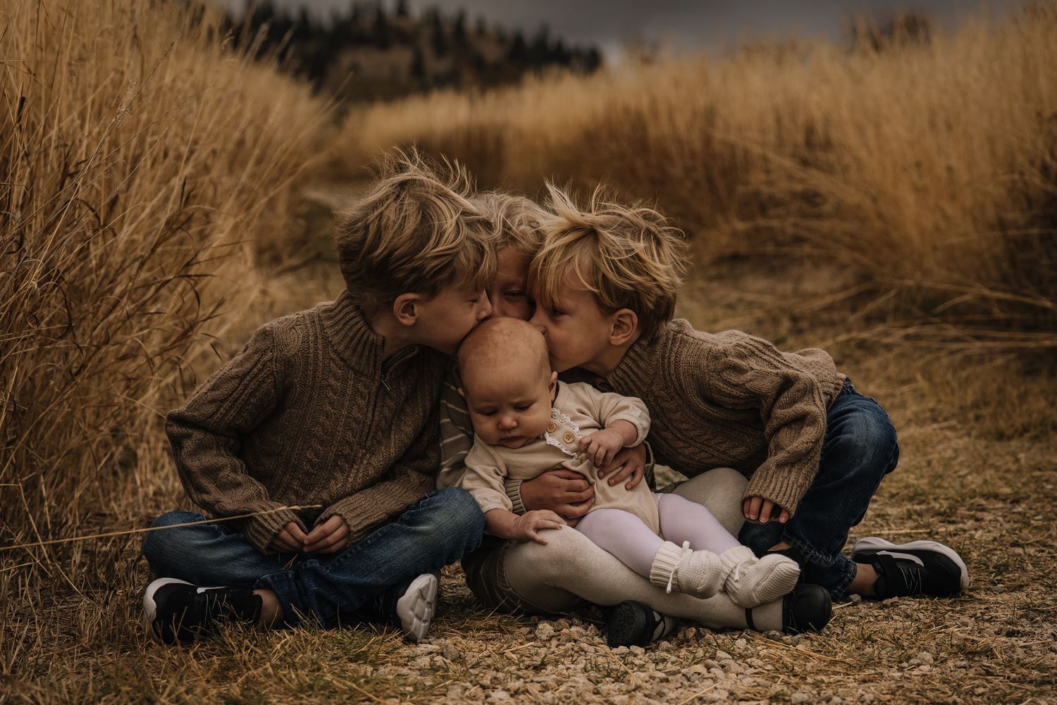 Candid family moments captured in warm tones among dry grass landscape.
