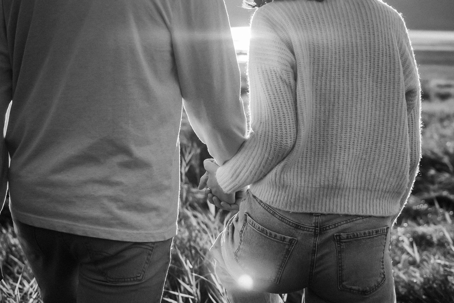 Close-up black and white shots of a couple in casual sweaters embracing outdoors.