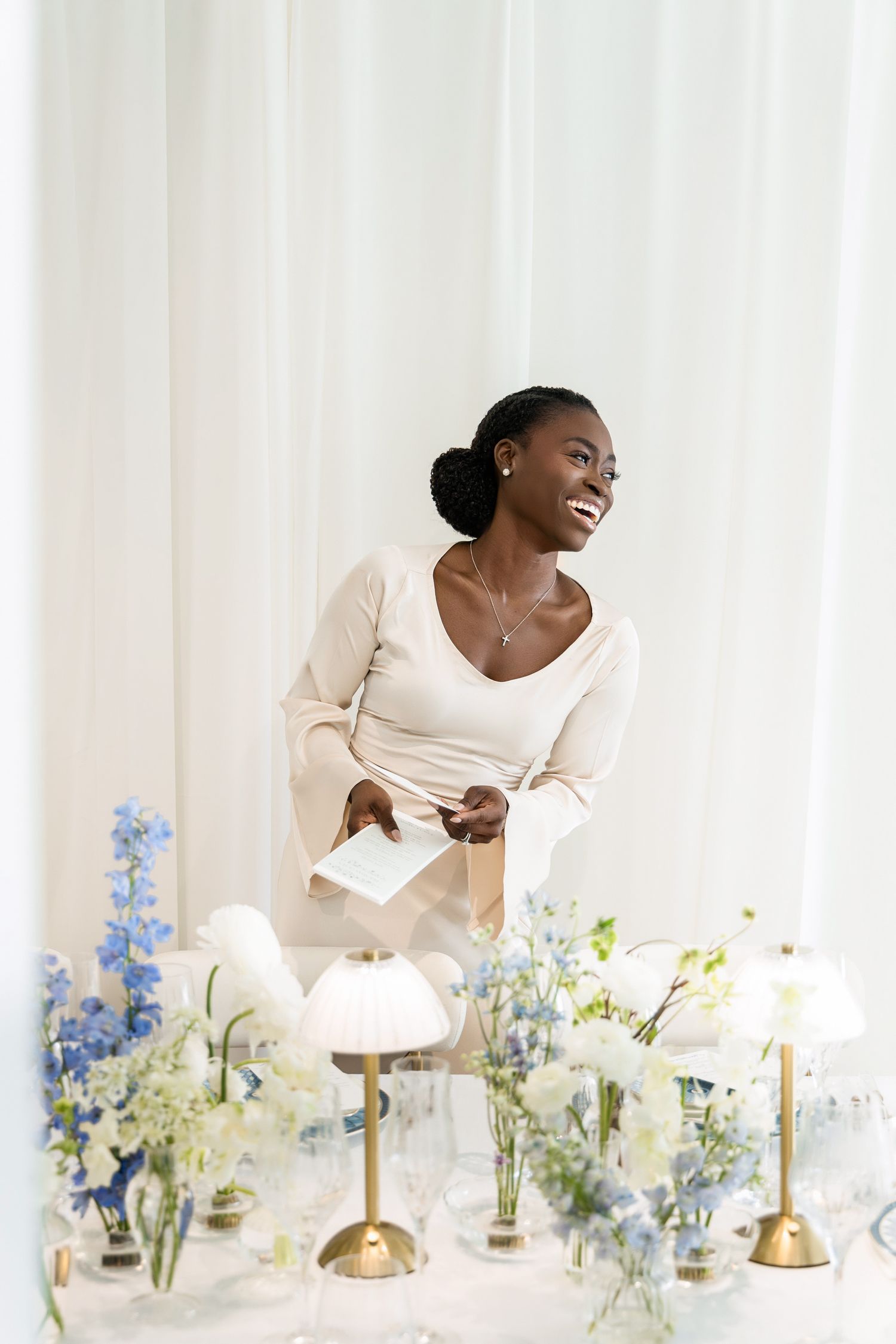 Luxury event planner reviewing notes beside an elegant blue and white tablescape with floral arrangements in Palm Beach, Florida.