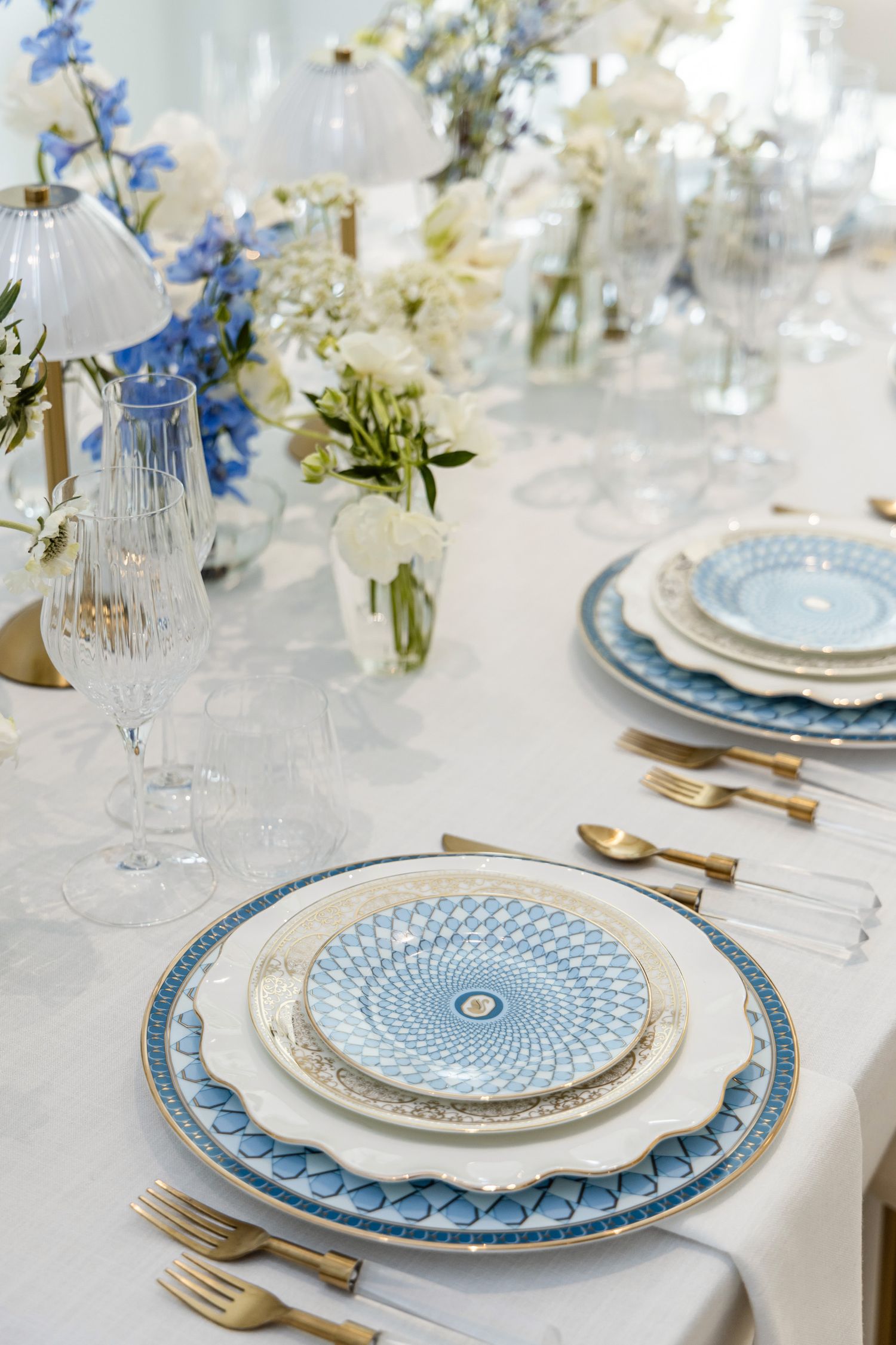 Elegant blue and white luxury tablescape with patterned china, crystal glassware, gold flatware, and florals in Palm Beach, Florida.