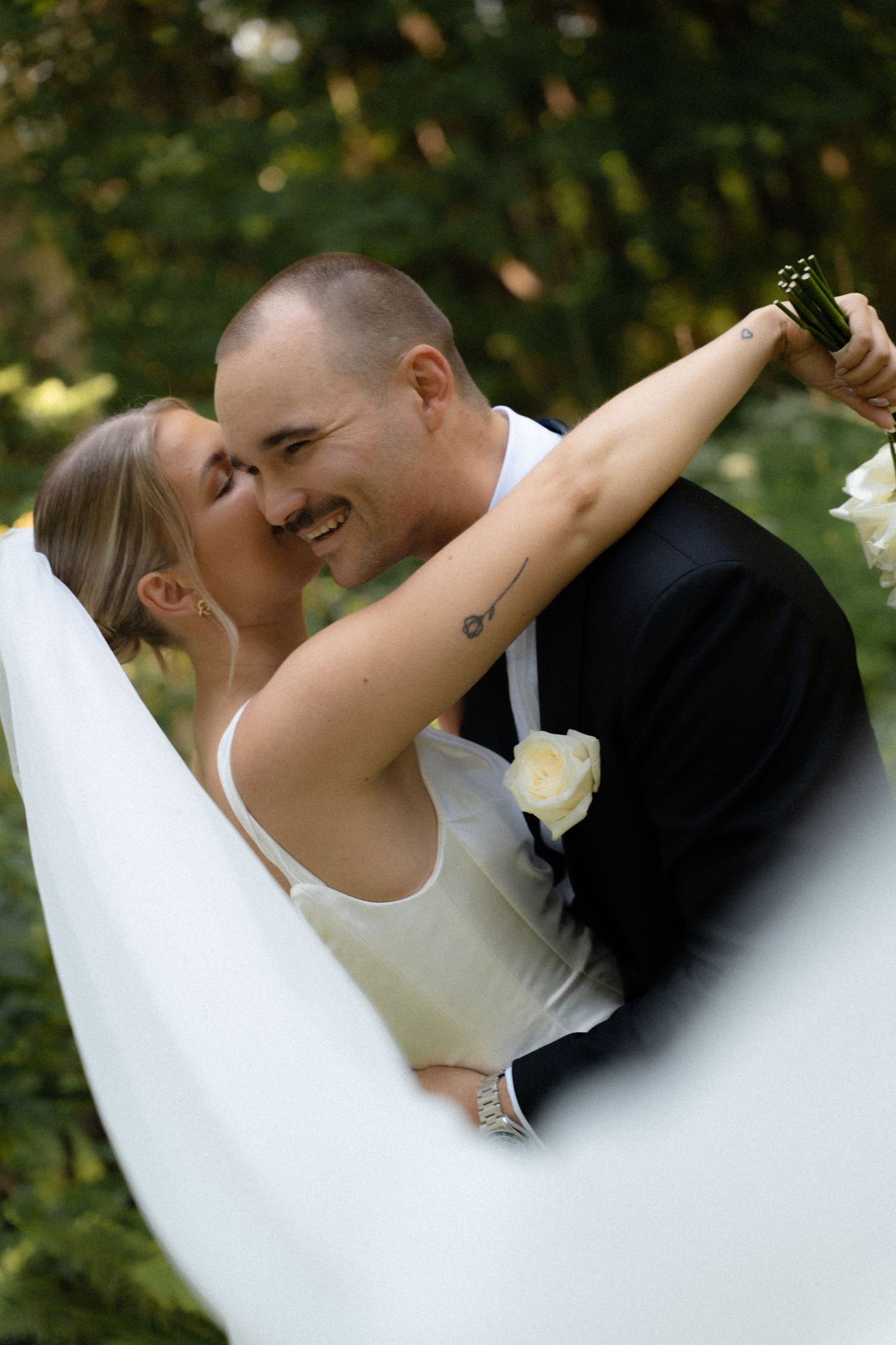 A romantic wedding couple shares intimate dance moves in a series of outdoor portraits with natural lighting and greenery.