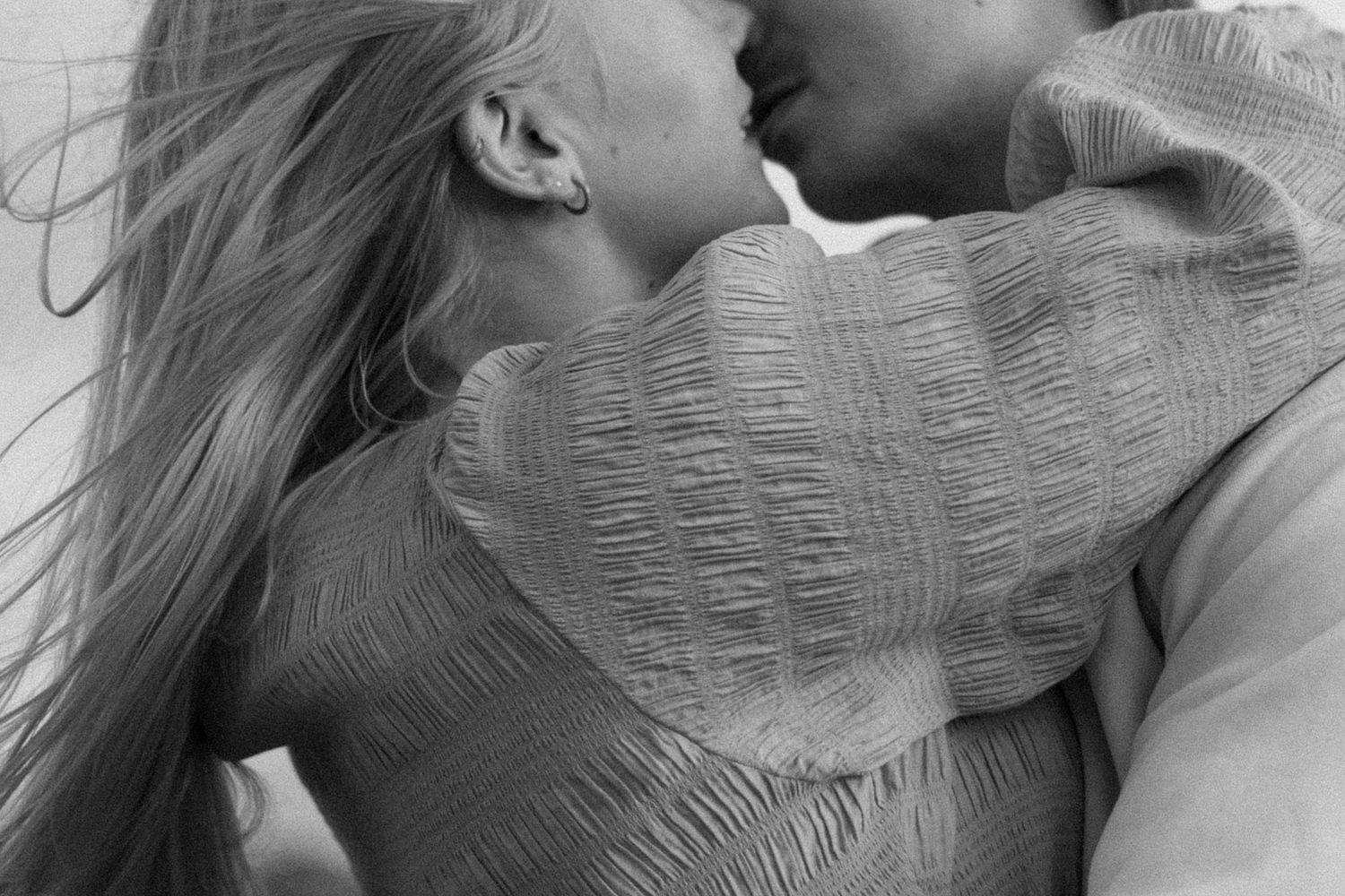 A romantic couple shares an intimate kiss in black and white.