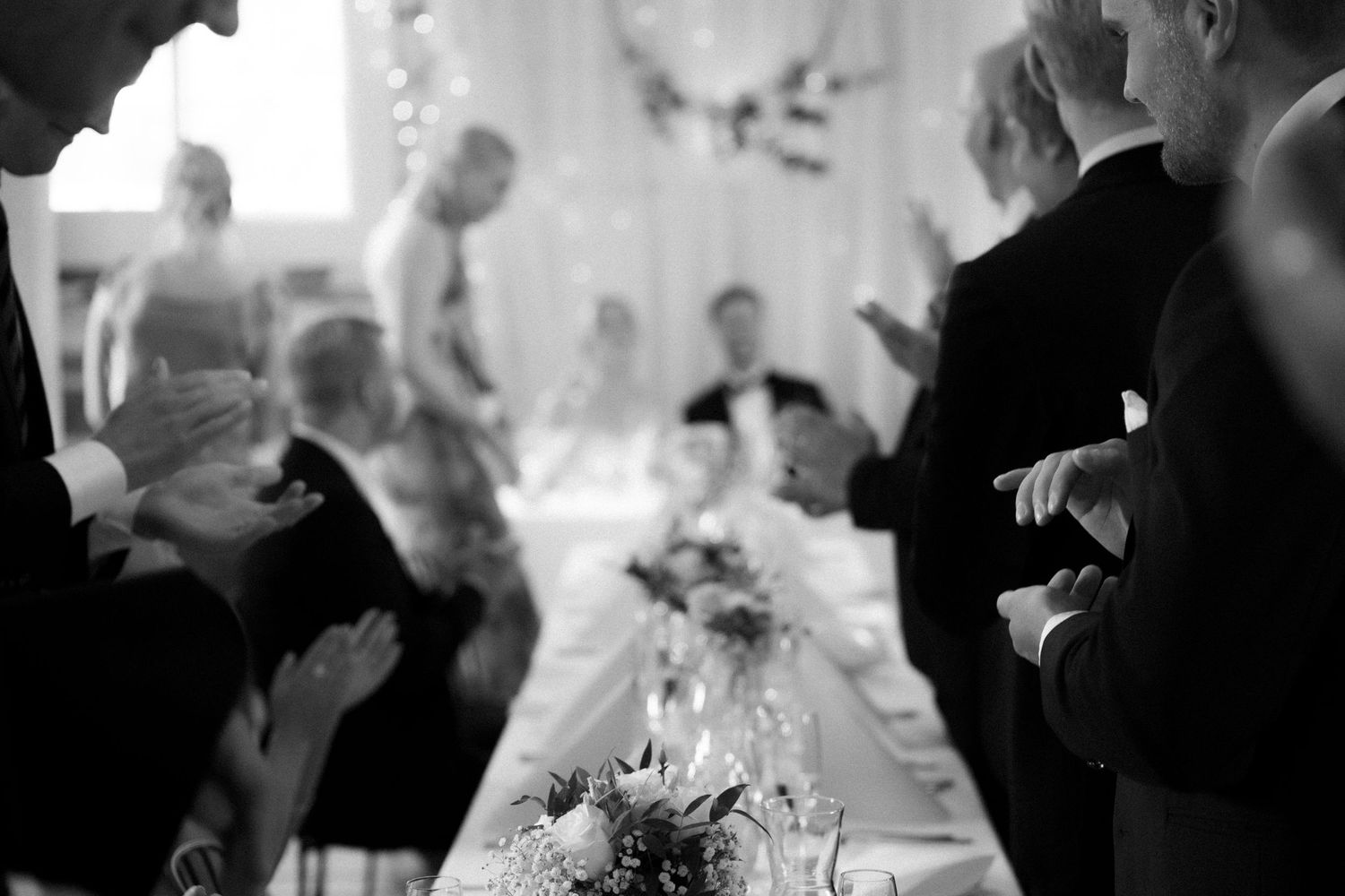 Wedding guests dancing and celebrating on a dance floor at an indoor reception venue.