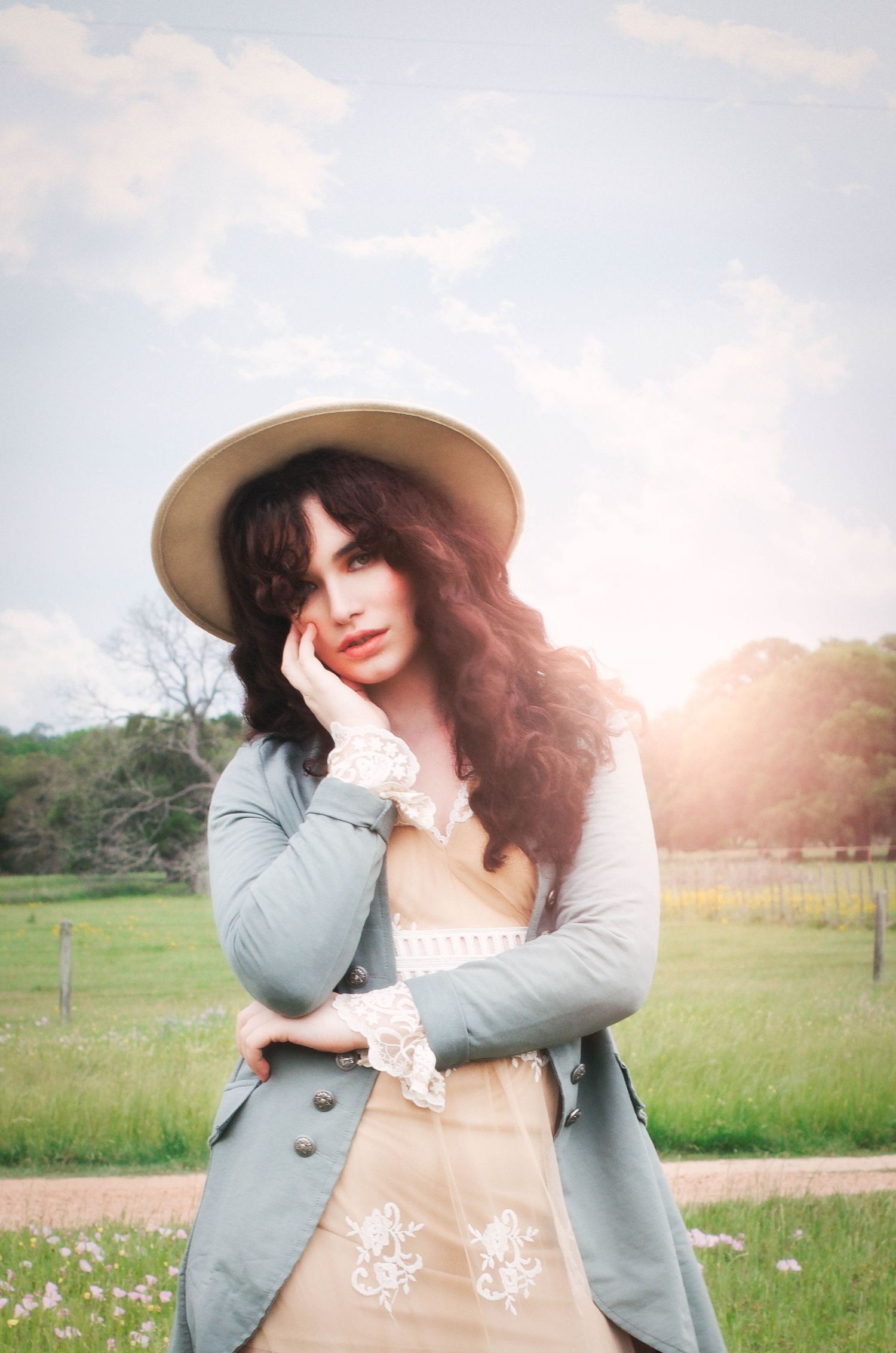 A dreamy outdoor photoshoot in a sunlit meadow featuring a girl in a green blazer and champagne lace dress.