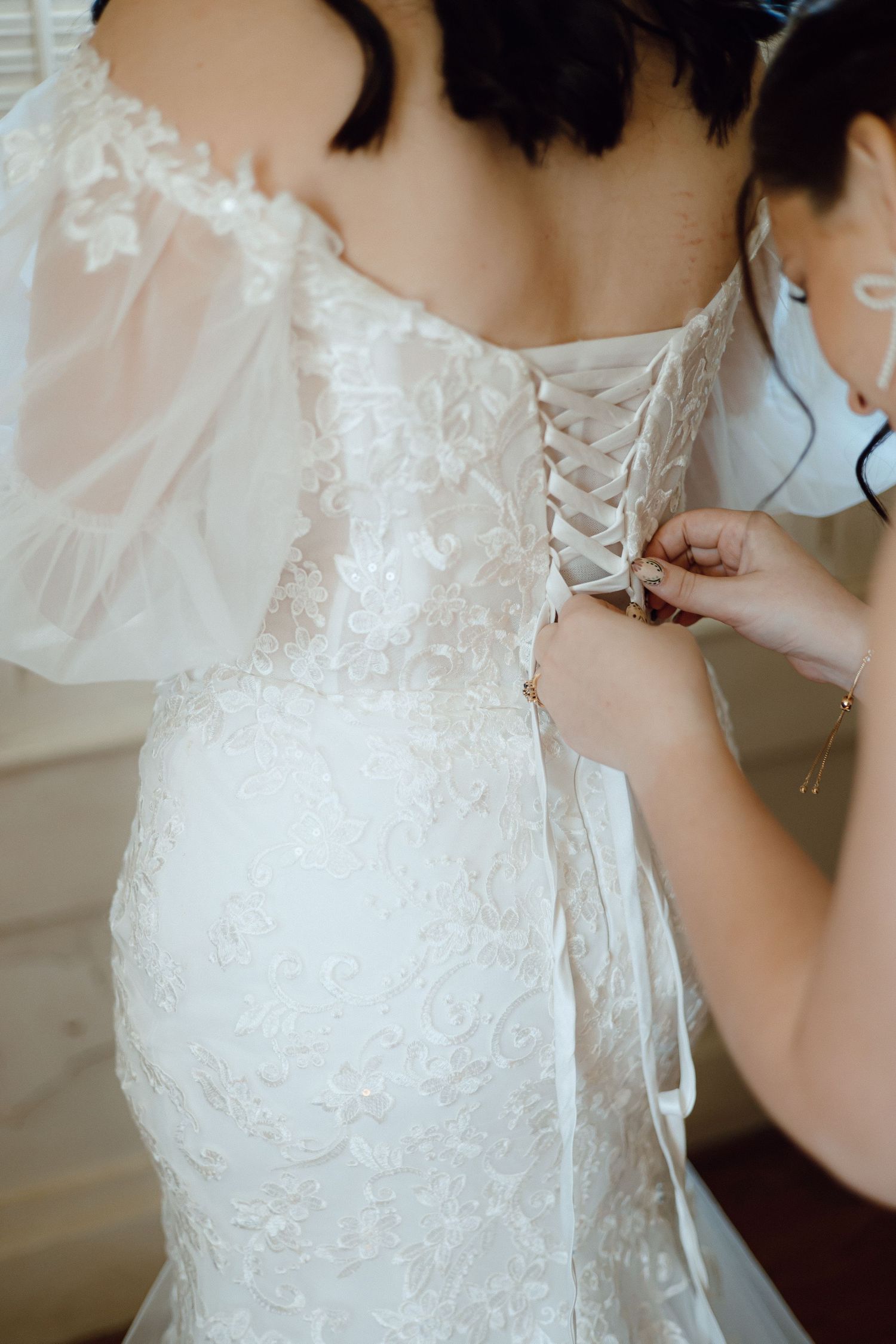 Detail shots of lacing up a white lace wedding dress.