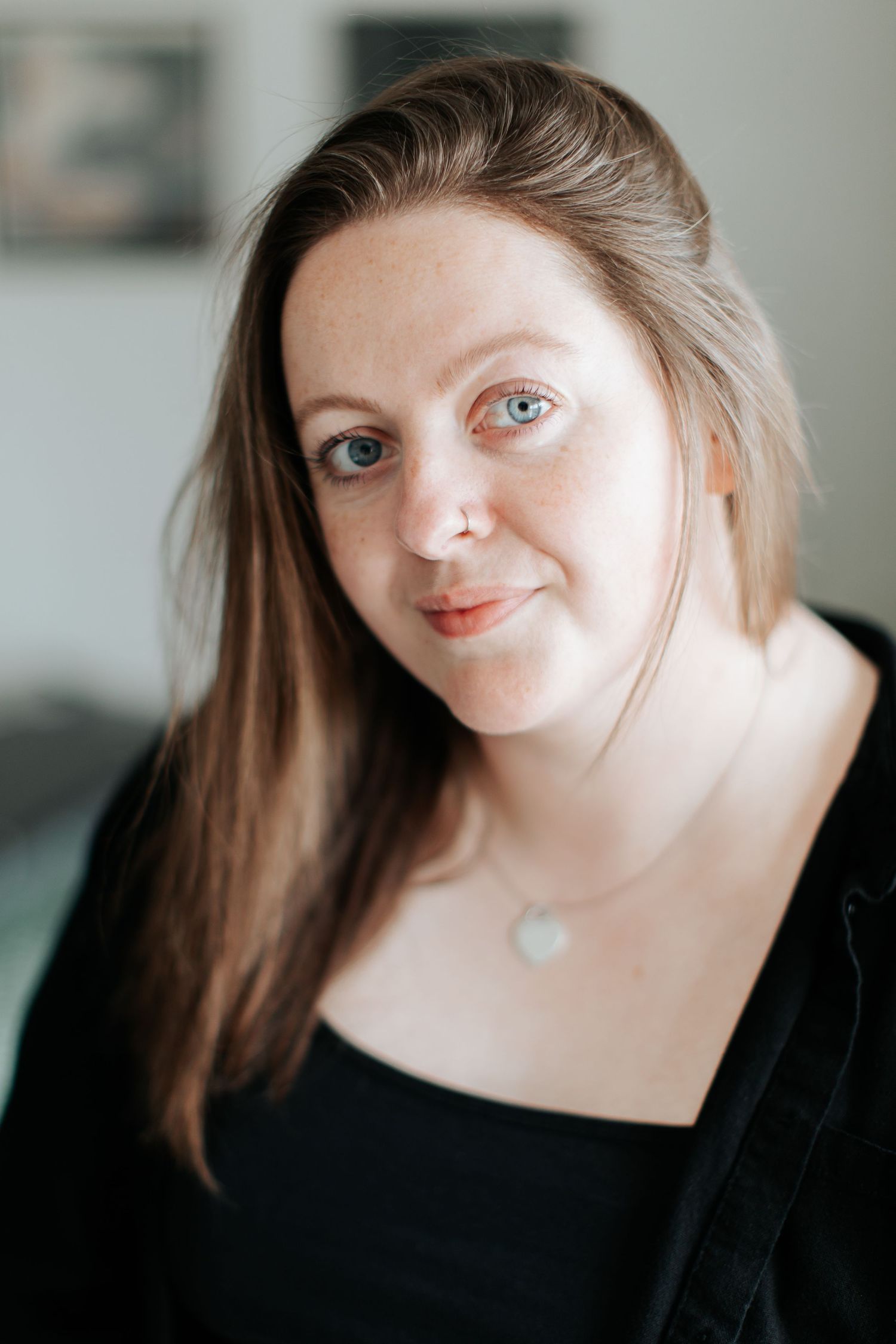 Close-up portrait of woman with long hair wearing black top and heart necklace.