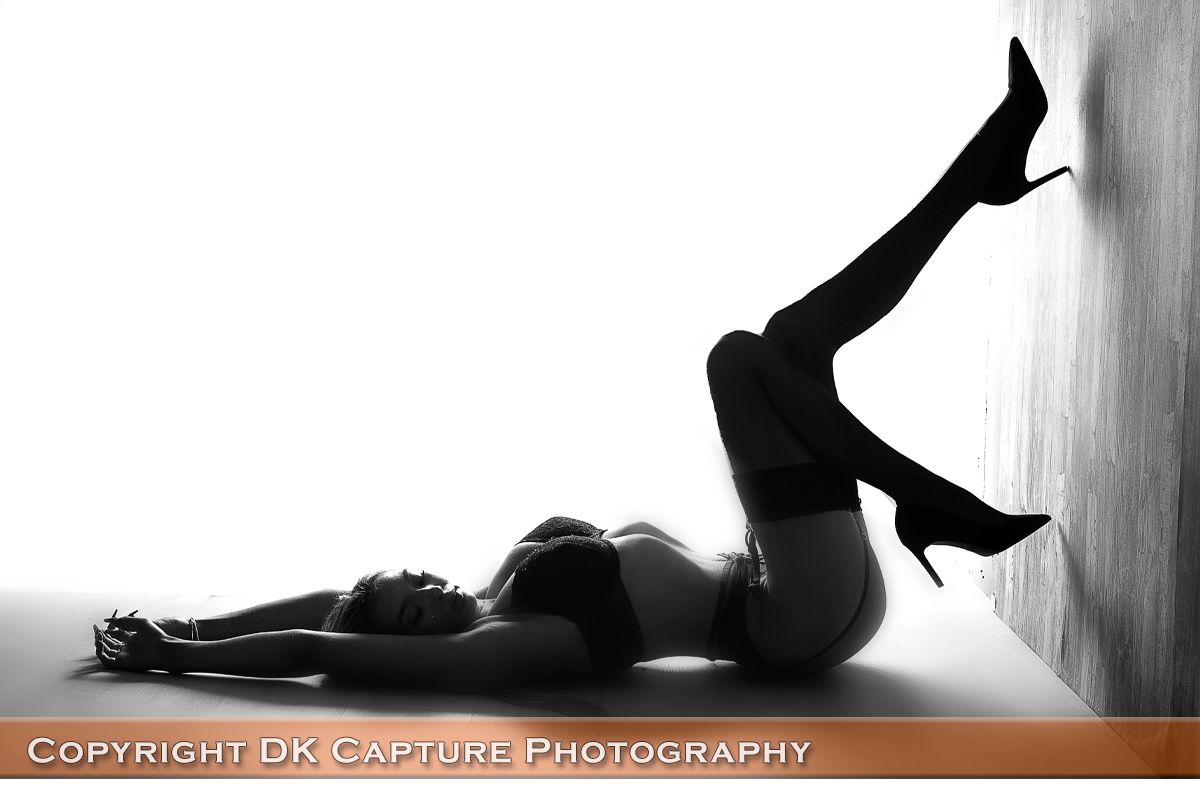 High contrast black and white silhouette against wall highlighting form and heels.