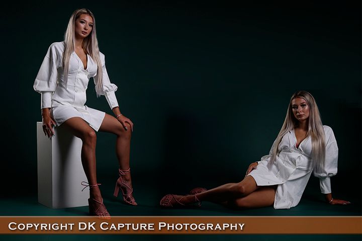 Professional studio photography session featuring artistic poses in white clothing against a dark background.