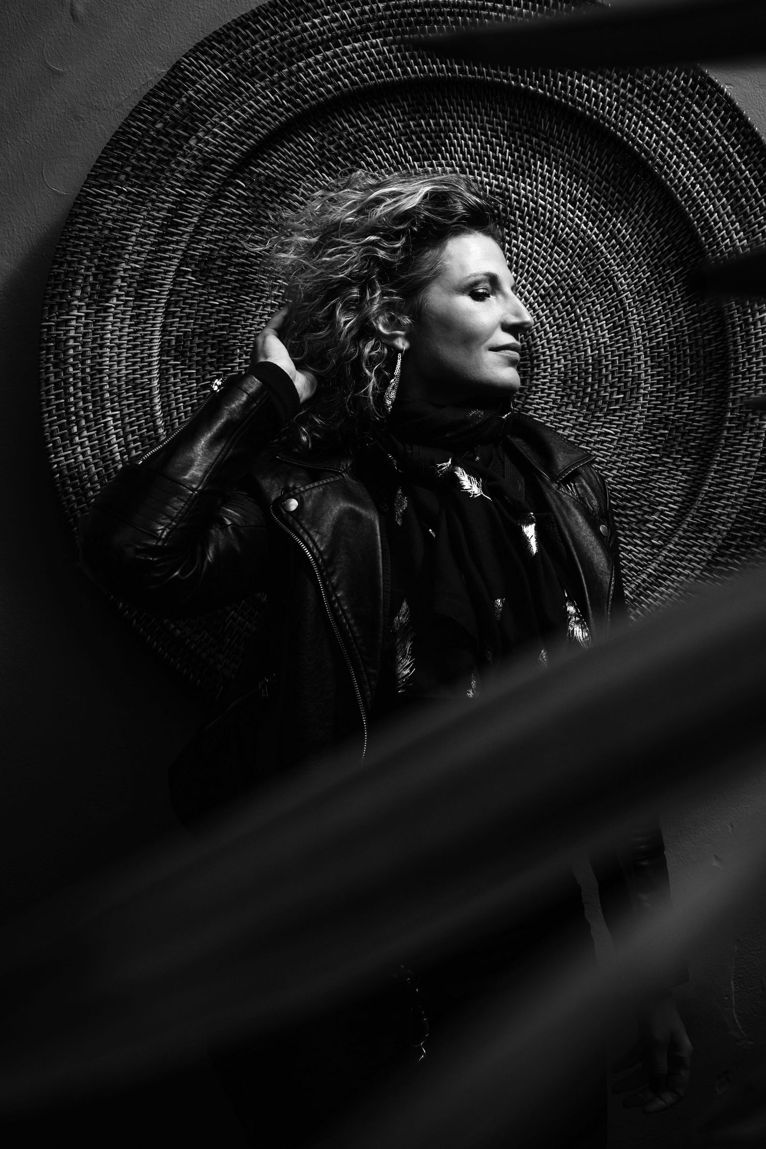 Black and white side profile portrait with dramatic lighting and curly hair against a textured background.