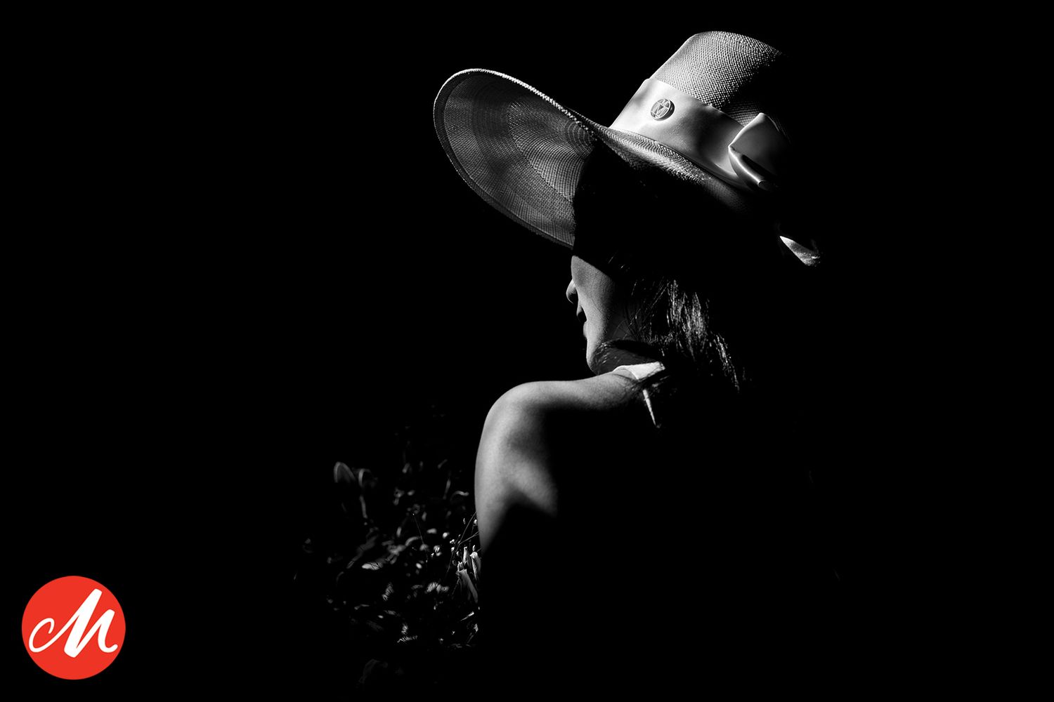 A dramatic black and white silhouette shows a cowboy in a wide-brimmed hat with camera against dark background.