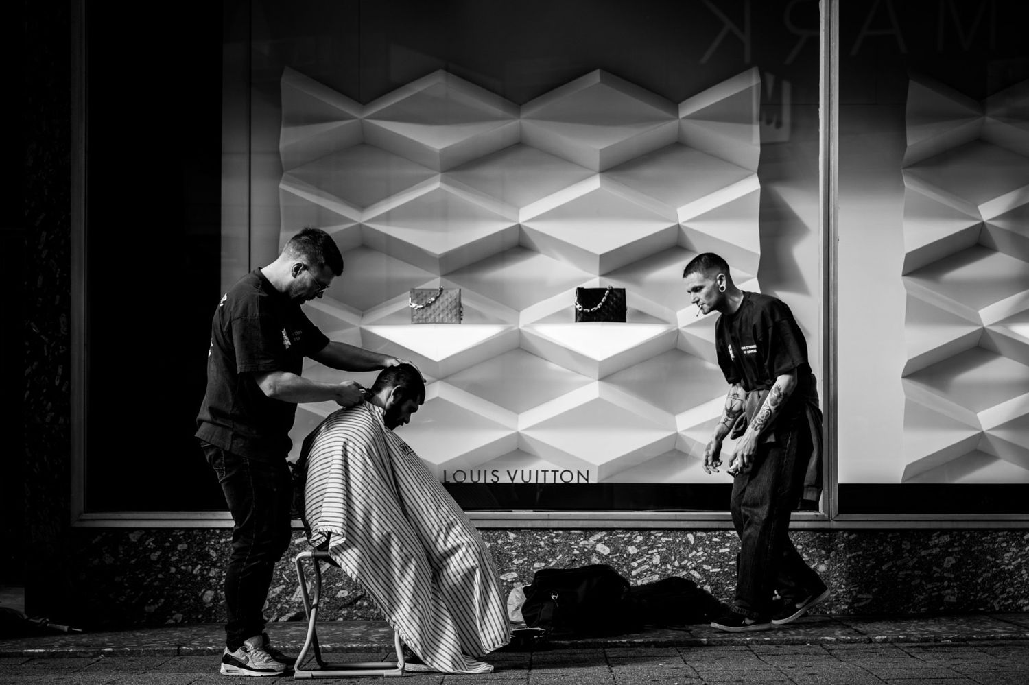 Skateboarders perform tricks on a geometric patterned floor in a black and white montage sequence.