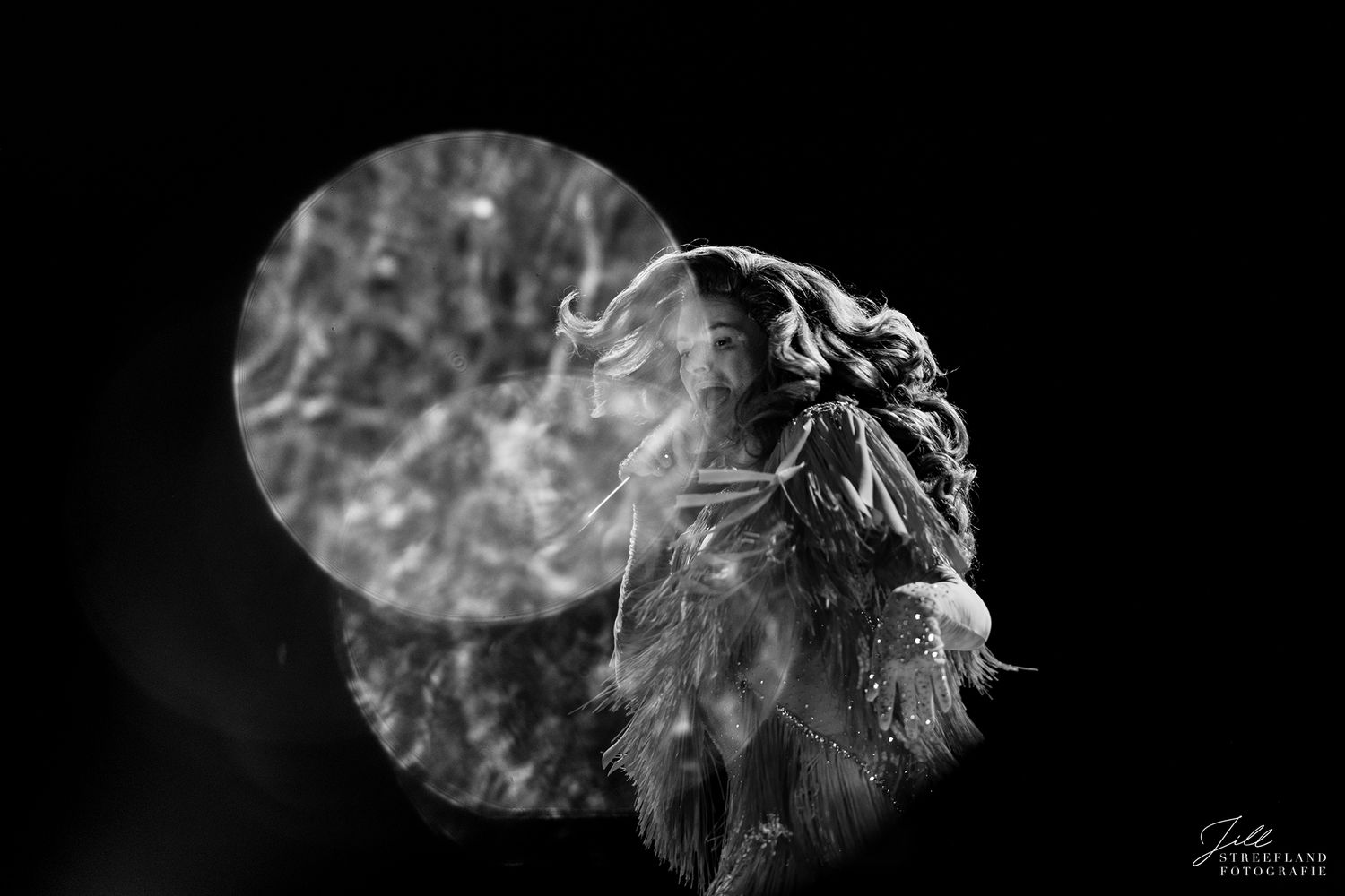 A dramatic black and white portrait of a lion's profile with windswept mane against a dark background.