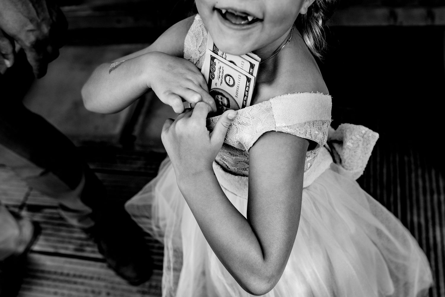 Black and white image of a child in a white dress laughing while holding something in their hands.