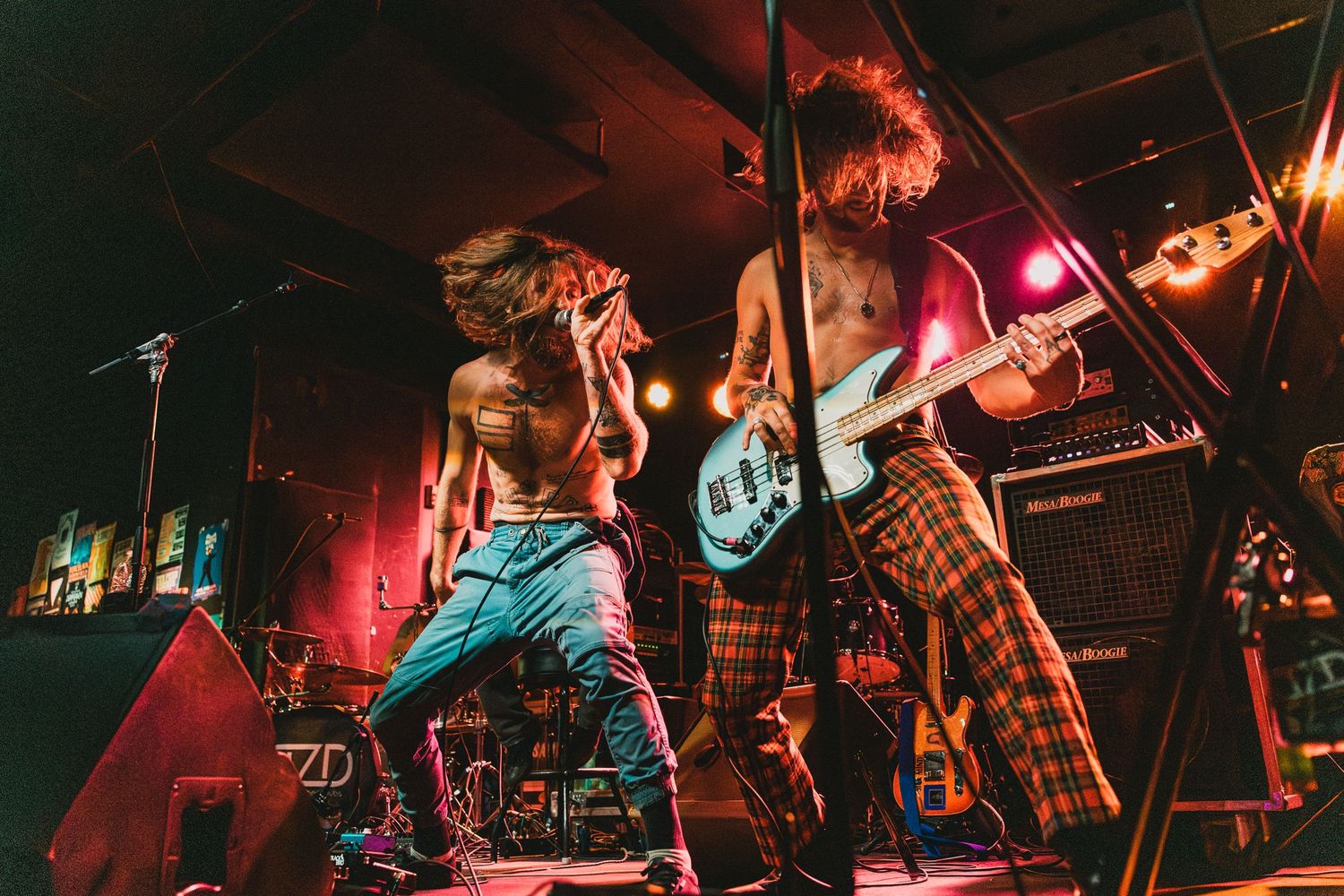 Band members performing with high energy under red stage lighting.