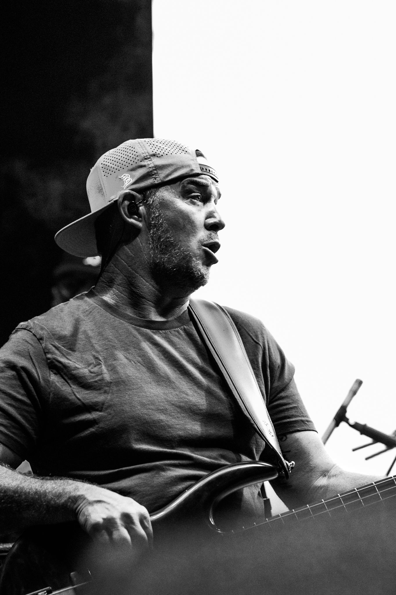 Musician in baseball cap performs passionately in dramatic black and white portrait.