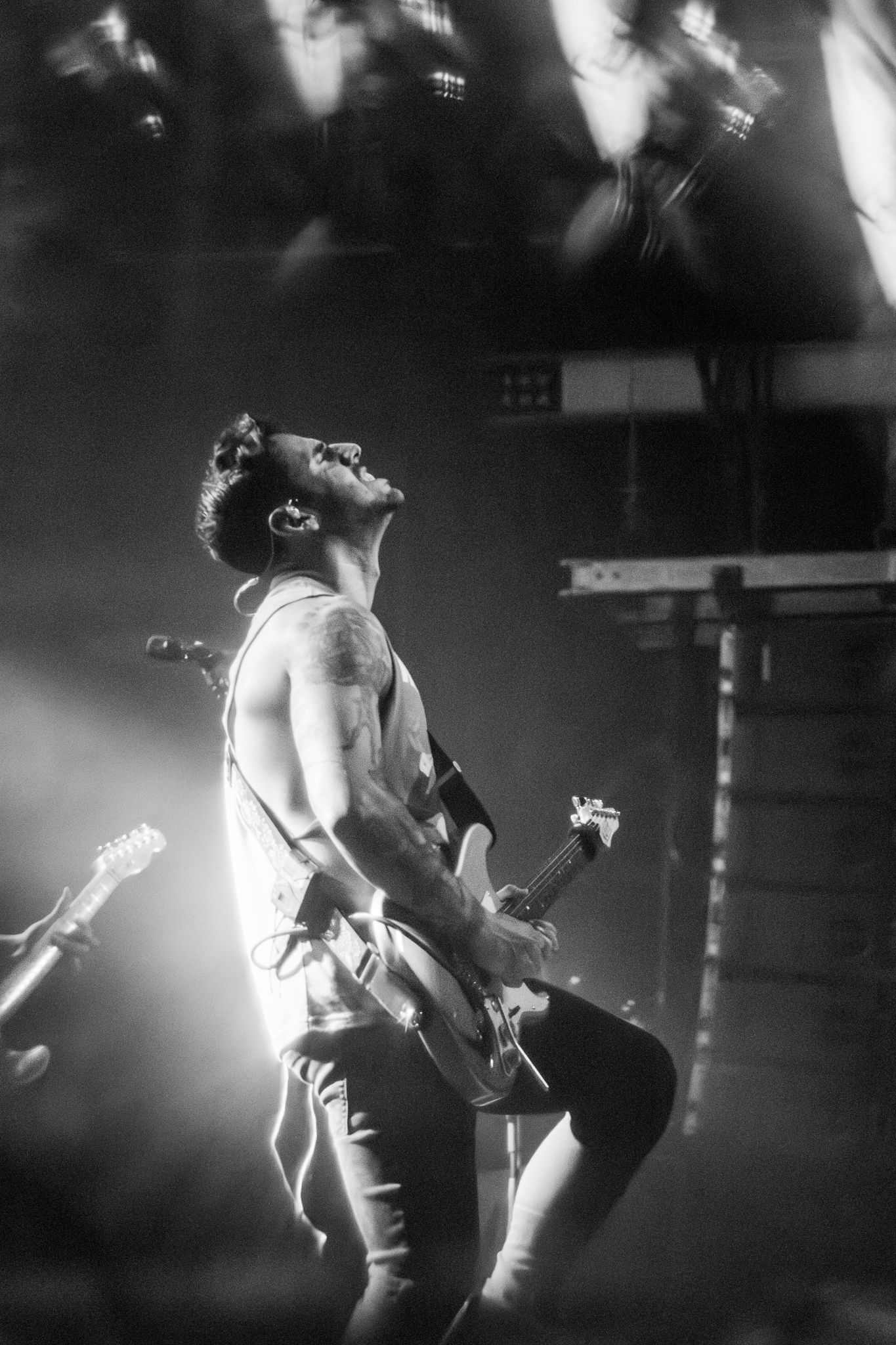 Musician plays electric guitar in dramatic black and white stage lighting.