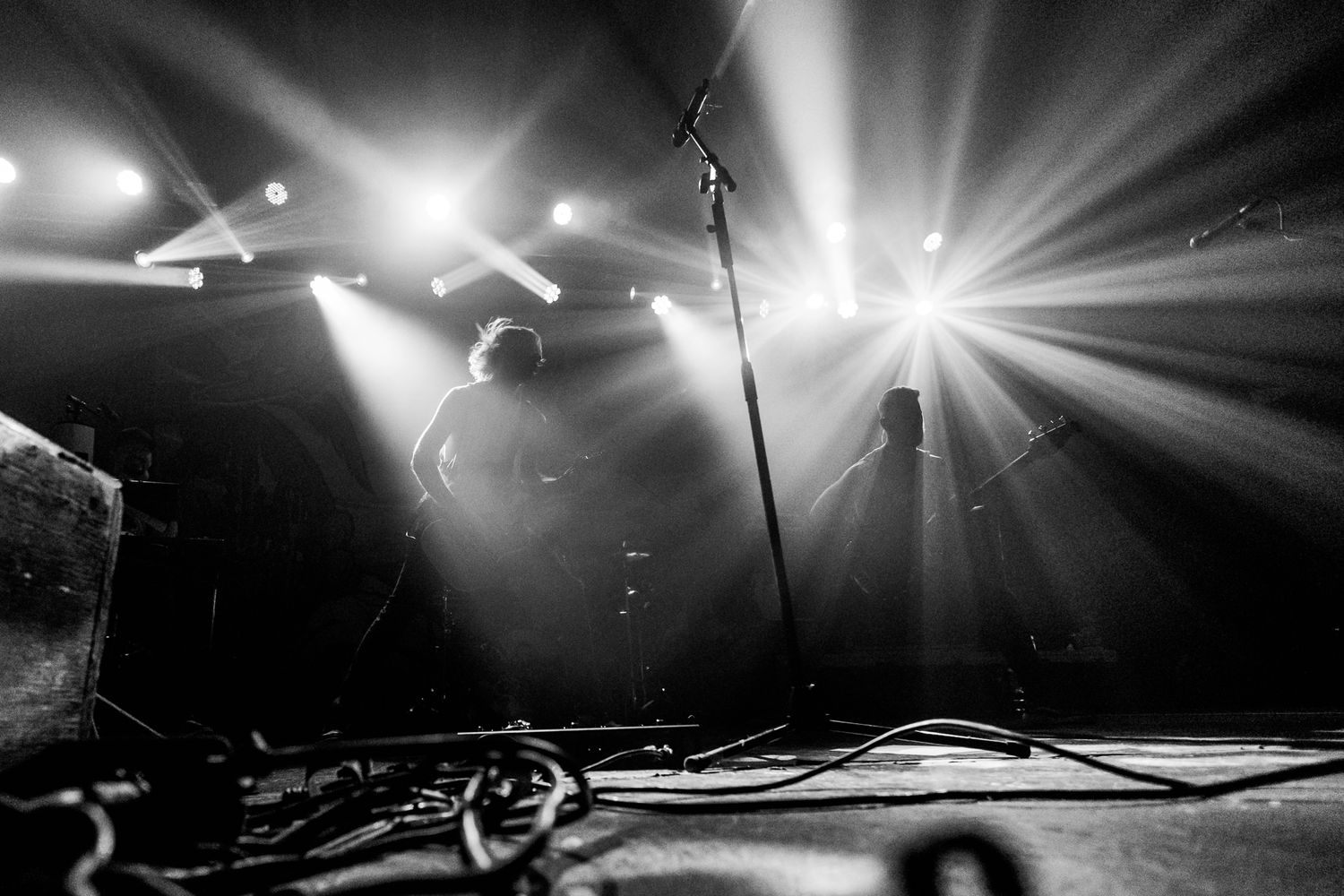 Dramatic black and white concert stage photo with bright starburst lighting effects.