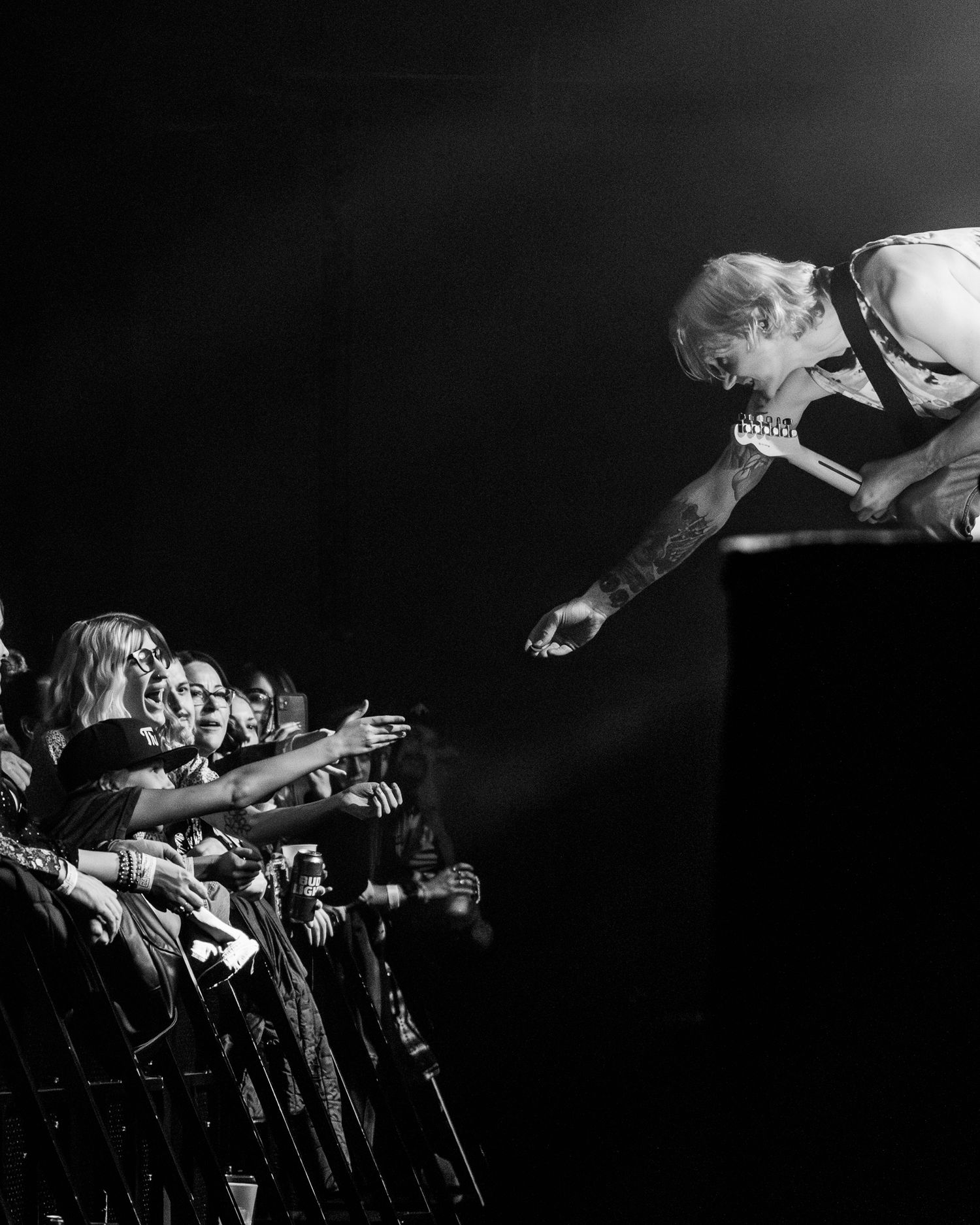 Dynamic concert photograph showing an interaction between performer and crowd at a barrier.