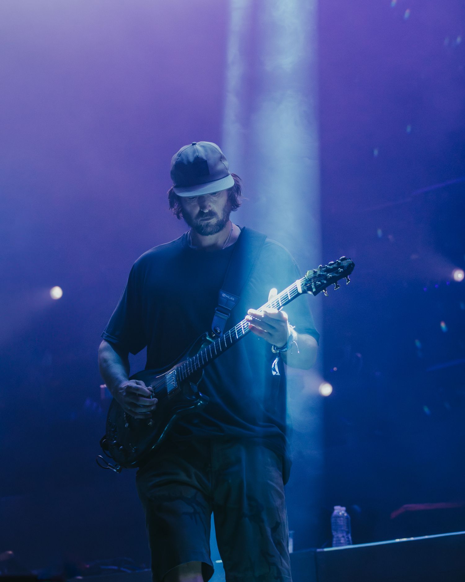 Guitarist performs in moody blue stage lighting creating an atmospheric concert scene.