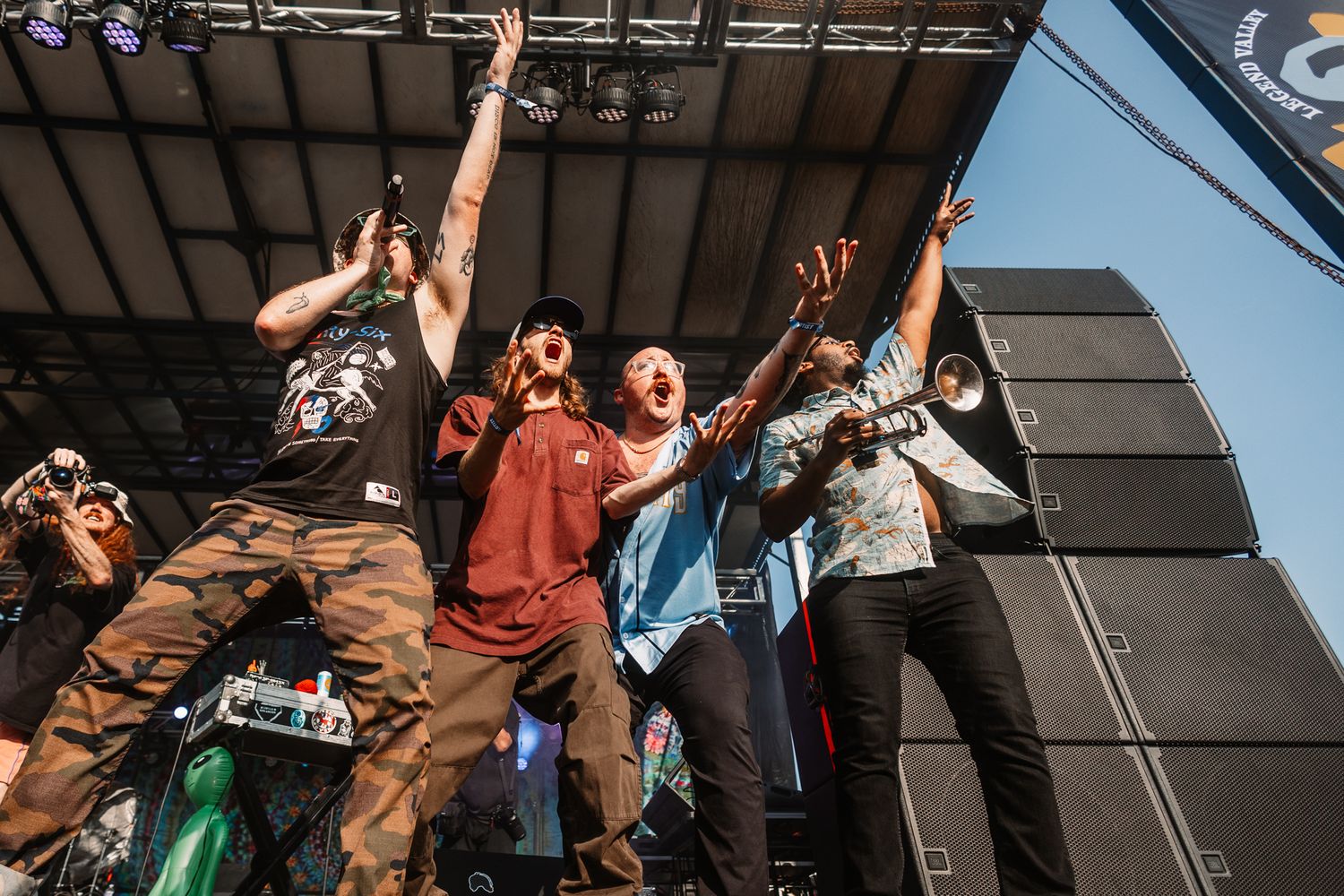 Group of performers raise their arms in unison during an energetic stage performance.