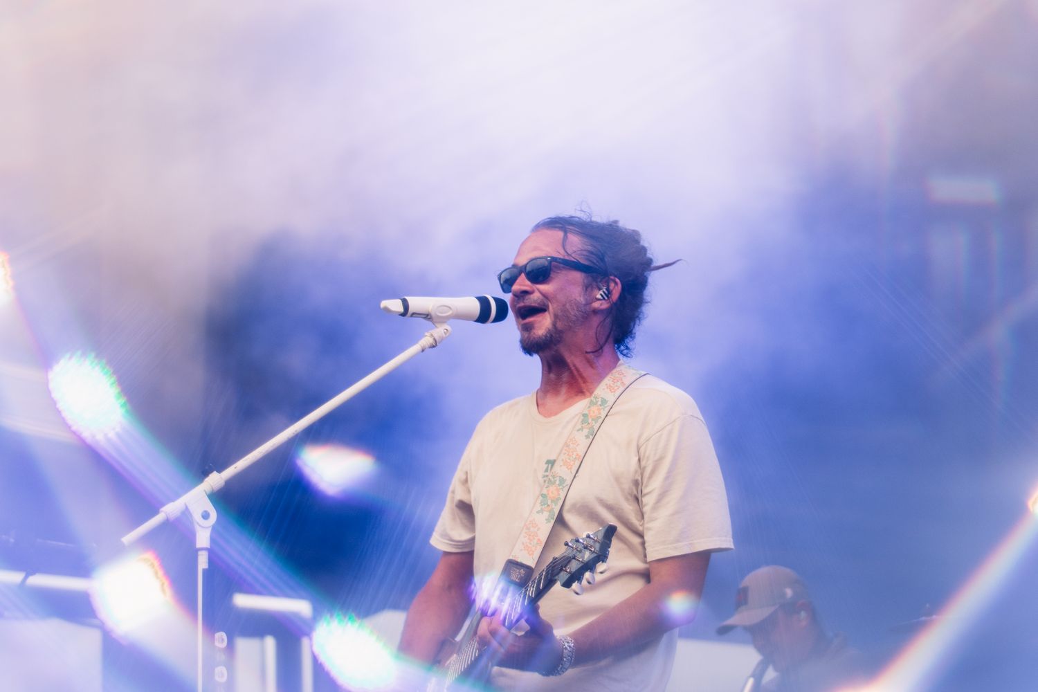Musician performs with guitar in atmospheric foggy stage lighting.