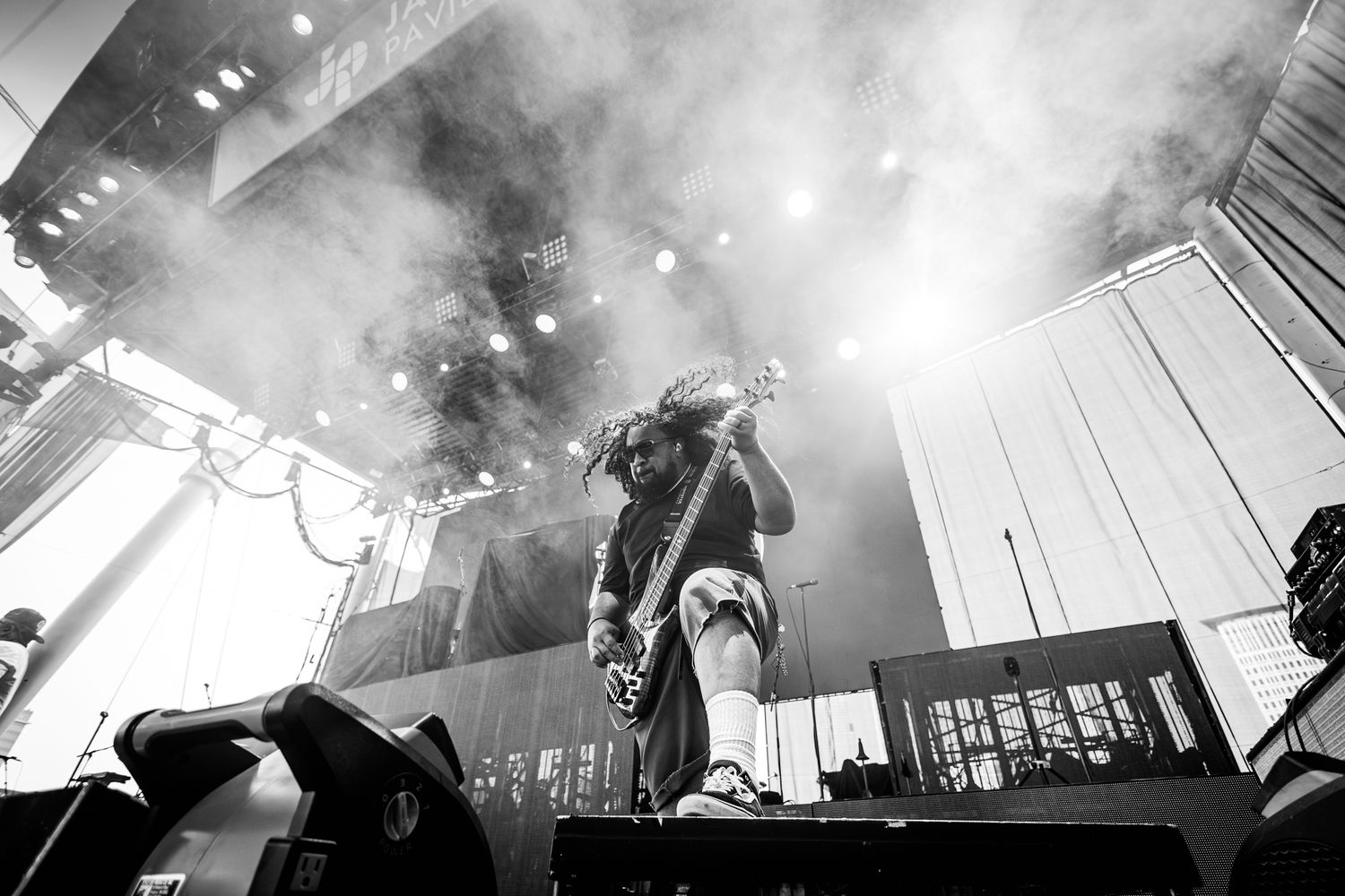 Dynamic black and white concert photo with performer silhouetted against bright stage lights.