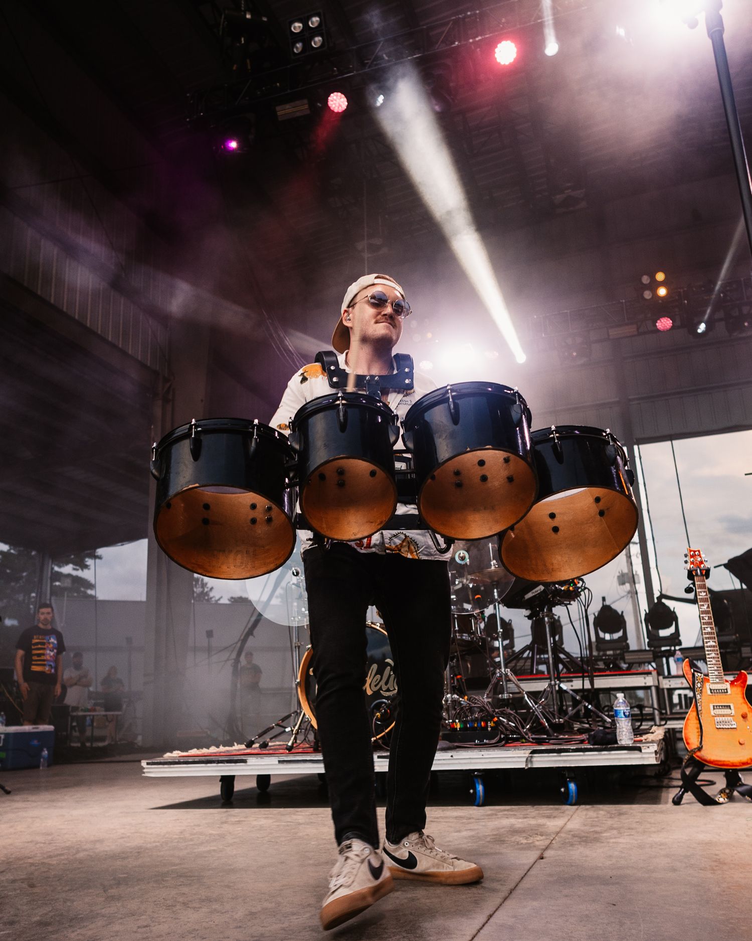 Drummer performing on stage with dramatic lighting and fog effects.