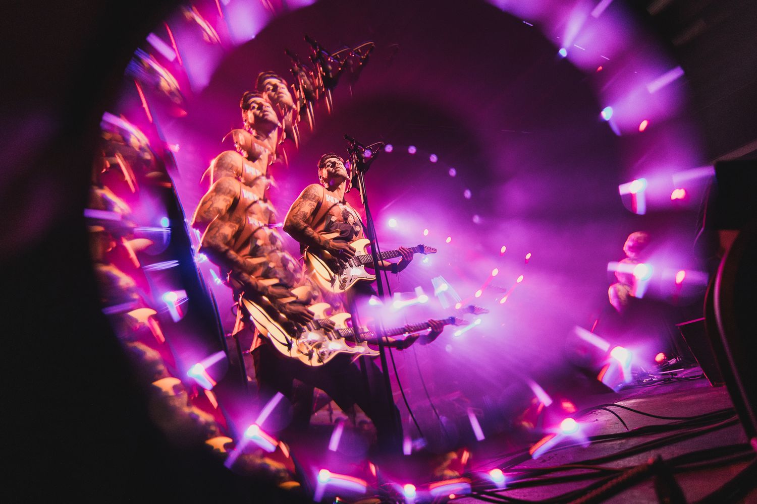 Concert performer captured in a swirling vortex of purple lighting effects on stage.