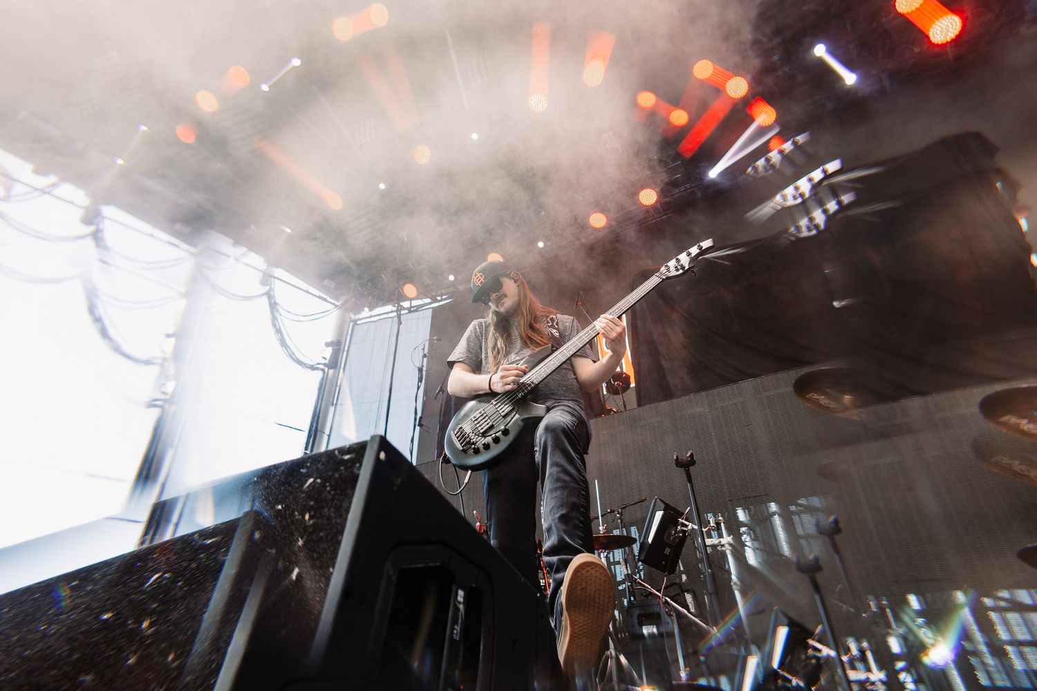 Concert performer playing guitar on stage with dramatic lighting and smoke effects in the background.