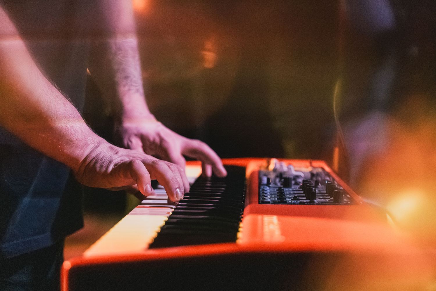 Close-up shot of hands playing electronic keyboard with warm lighting.