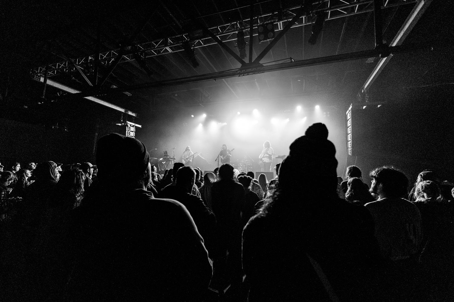 Silhouetted crowd watching a concert with dramatic stage lighting in the background.