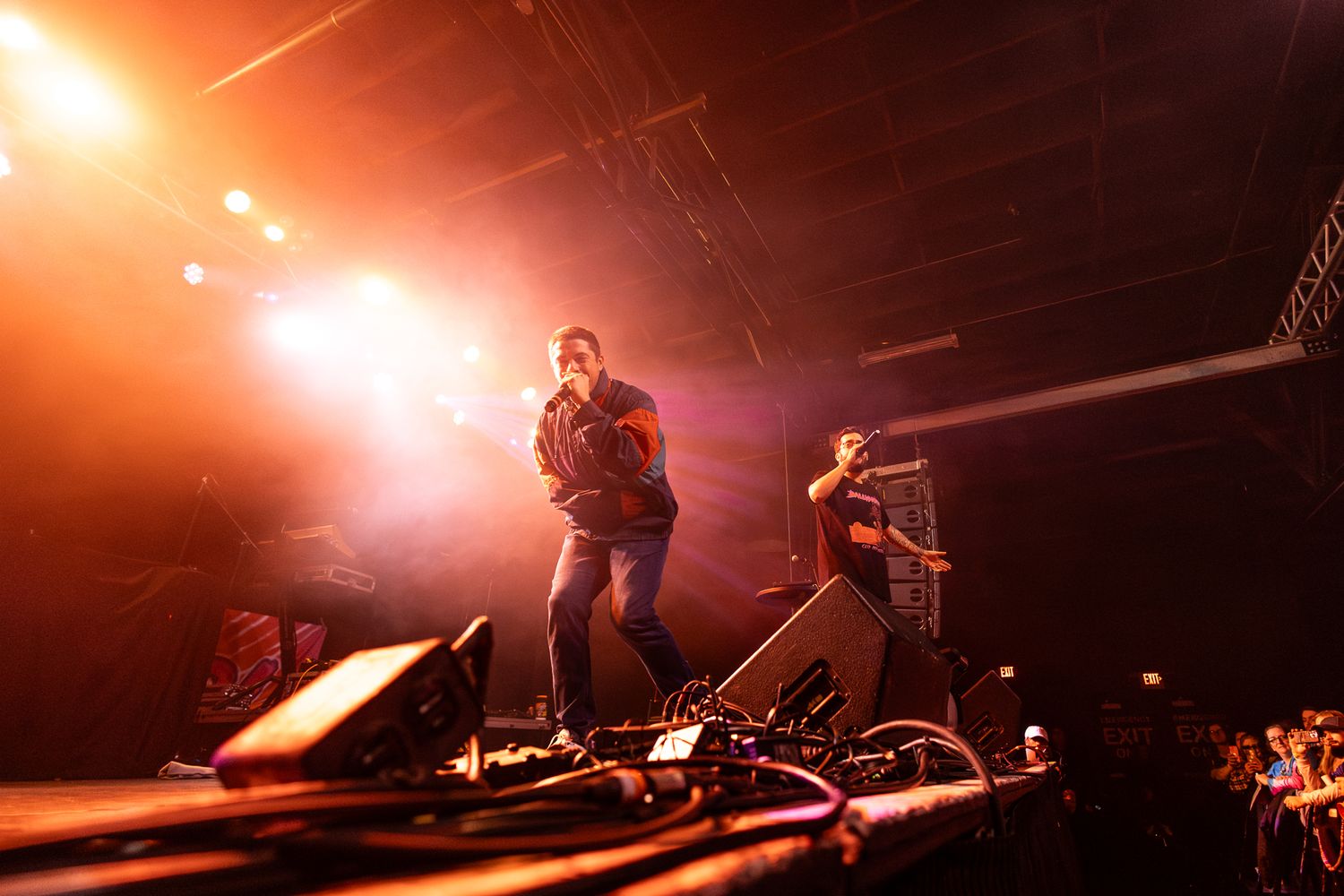 Concert performers silhouetted against warm orange stage lighting during an energetic show.