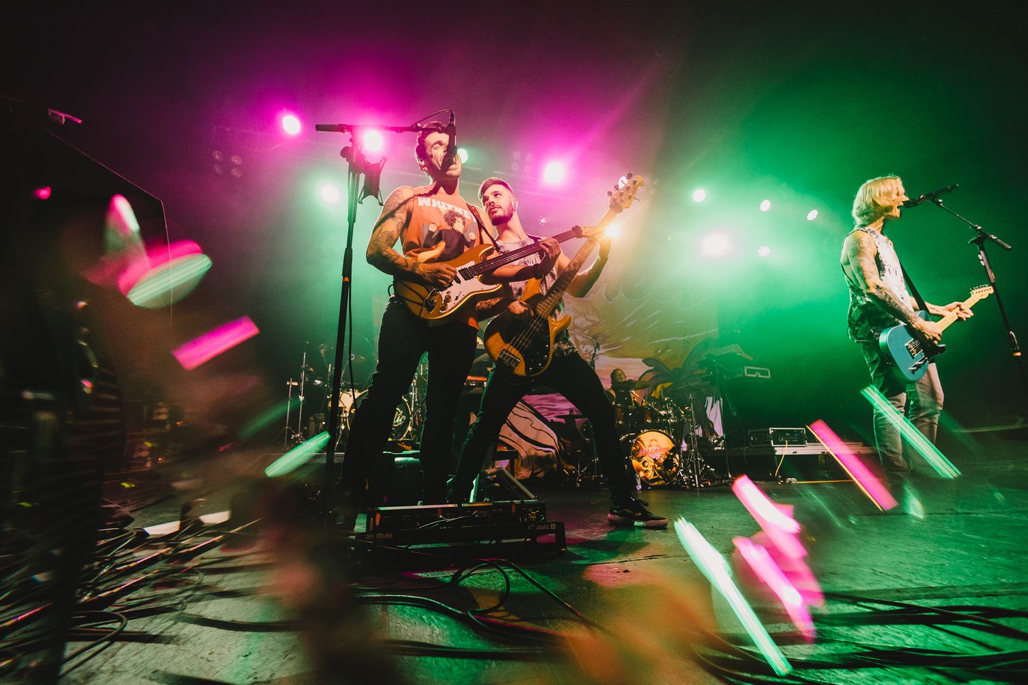 Band performing on stage with vibrant pink and green lighting creating an energetic atmosphere.