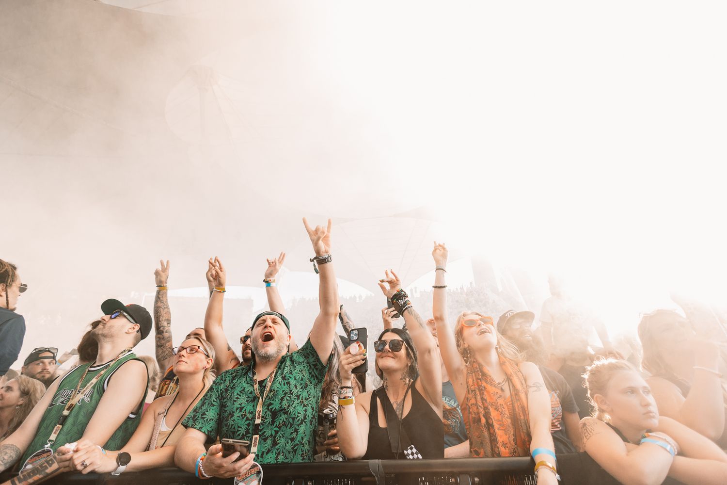 Concert crowd raises hands in celebration during sunset music festival.