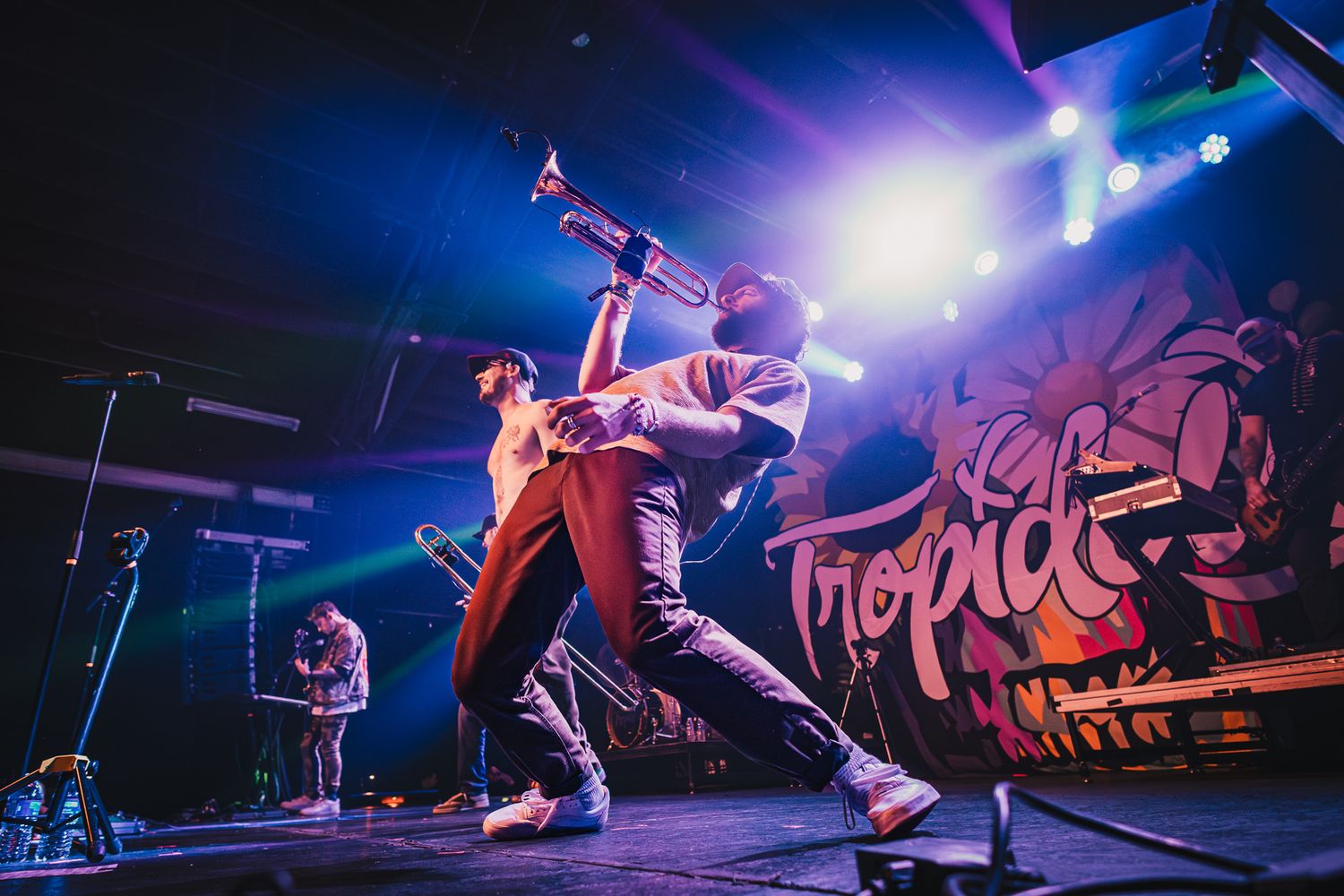 Energetic concert performance with colorful blue lighting and graffiti backdrop on stage.