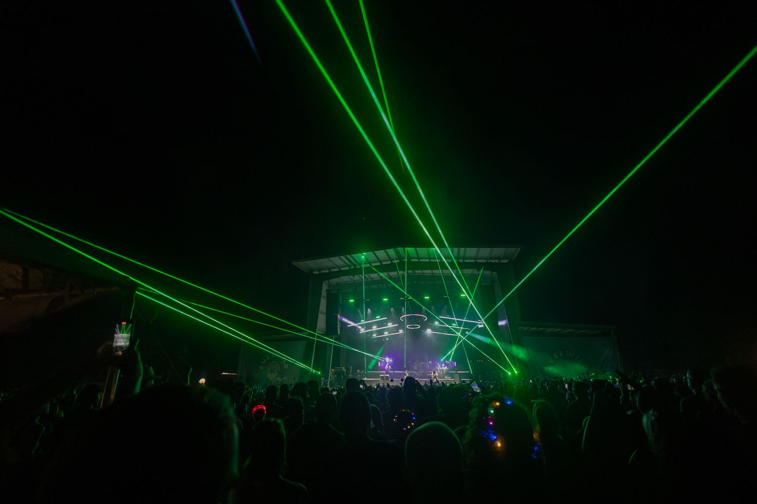 Green laser beams illuminate concert venue during nighttime performance.