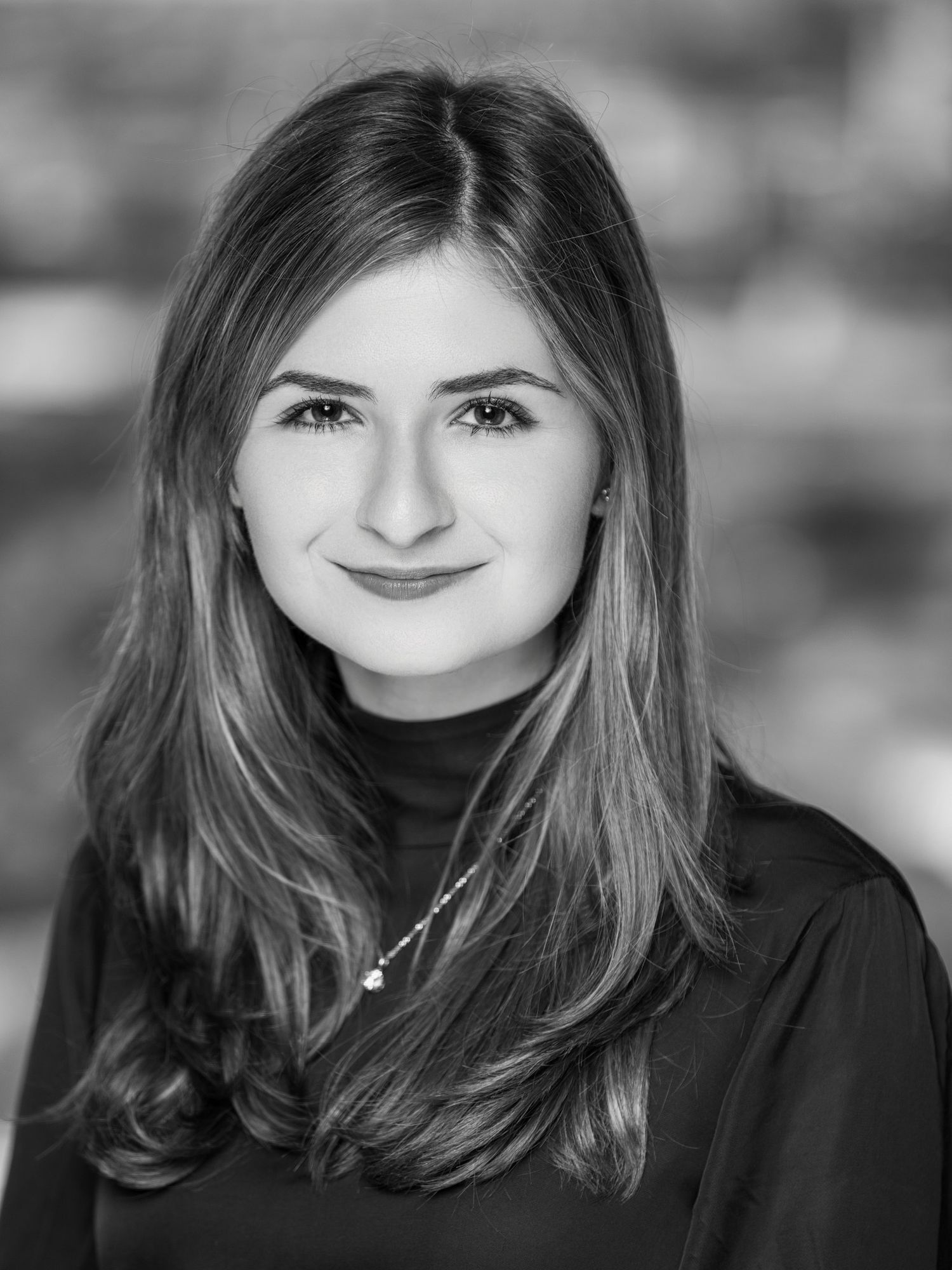 Professional black and white headshot portrait with soft lighting and blurred background.